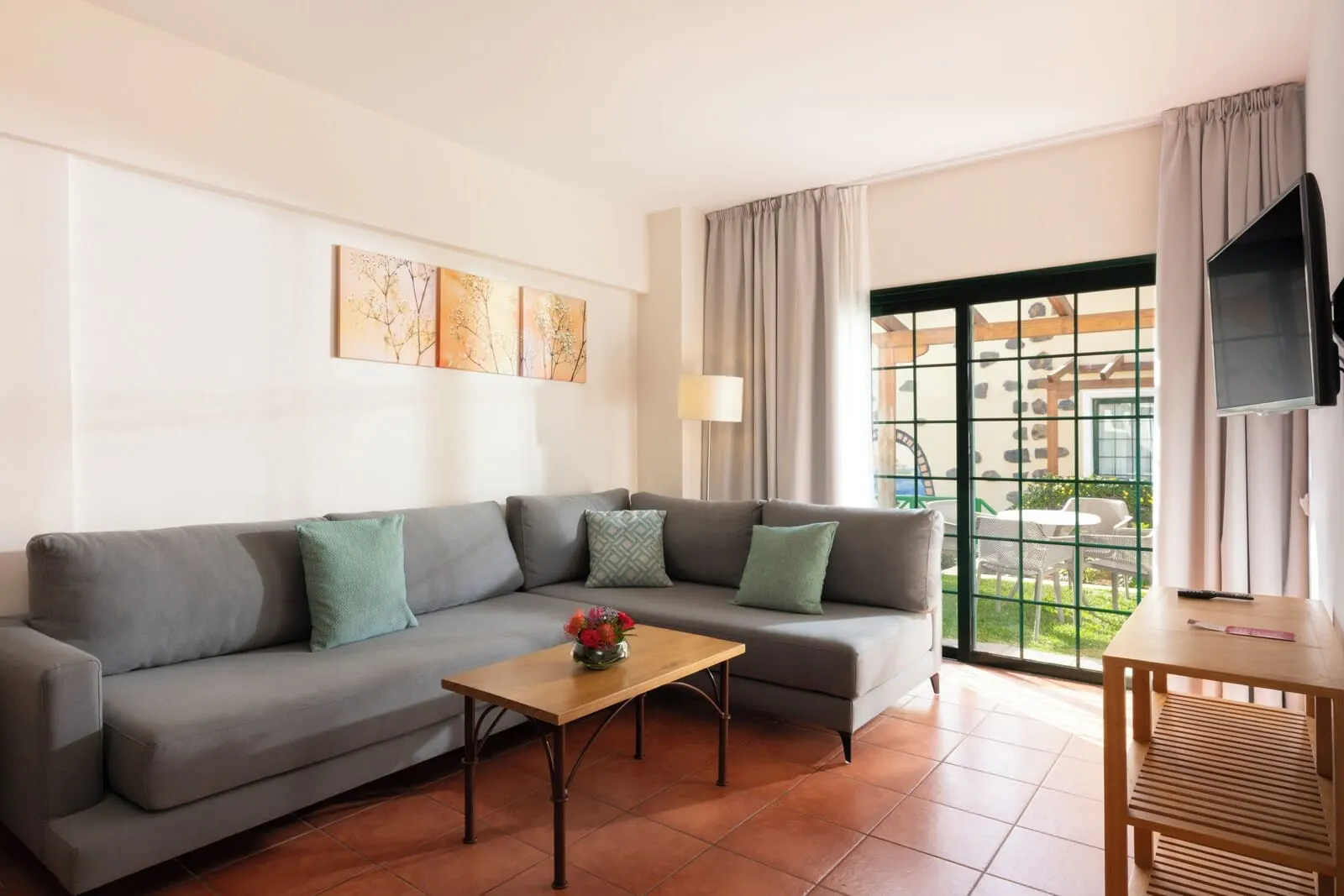 GF Isabel: A modern living room with a grey sofa, a wooden coffee table, and a TV on a stand