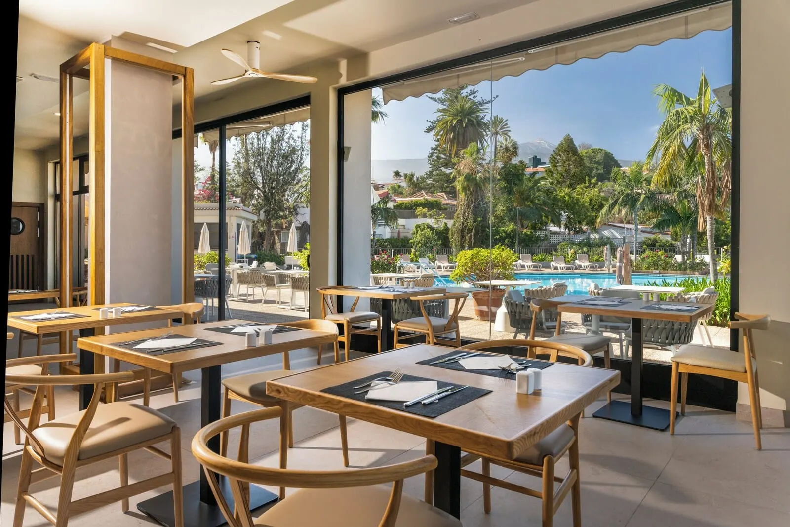 Hotel Atlantic El Tope: A restaurant with outdoor seating overlooking a pool and mountains. Tables are set