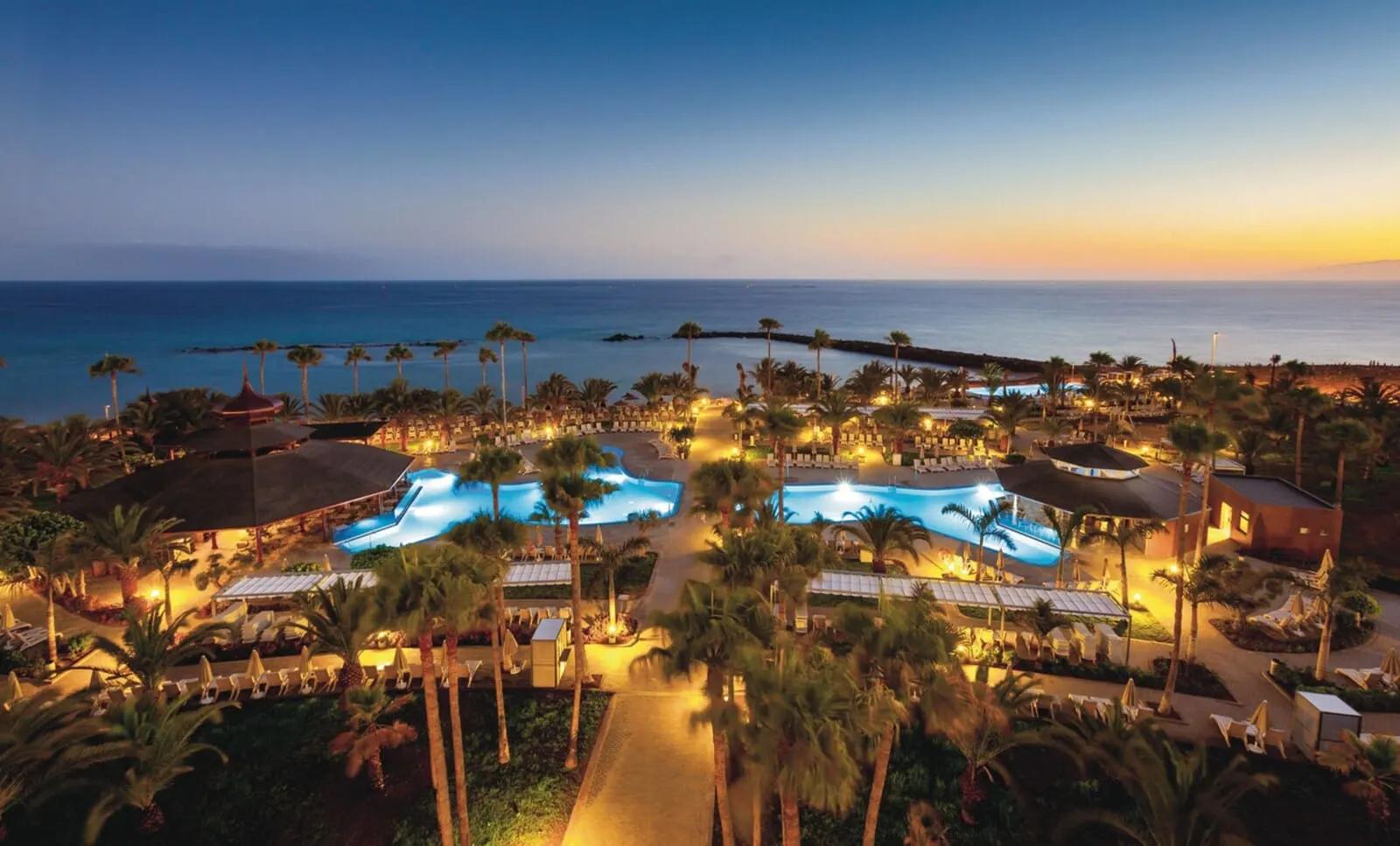 Hotel Riu Palace Tenerife: An aerial view of a resort with multiple swimming pools, palm trees