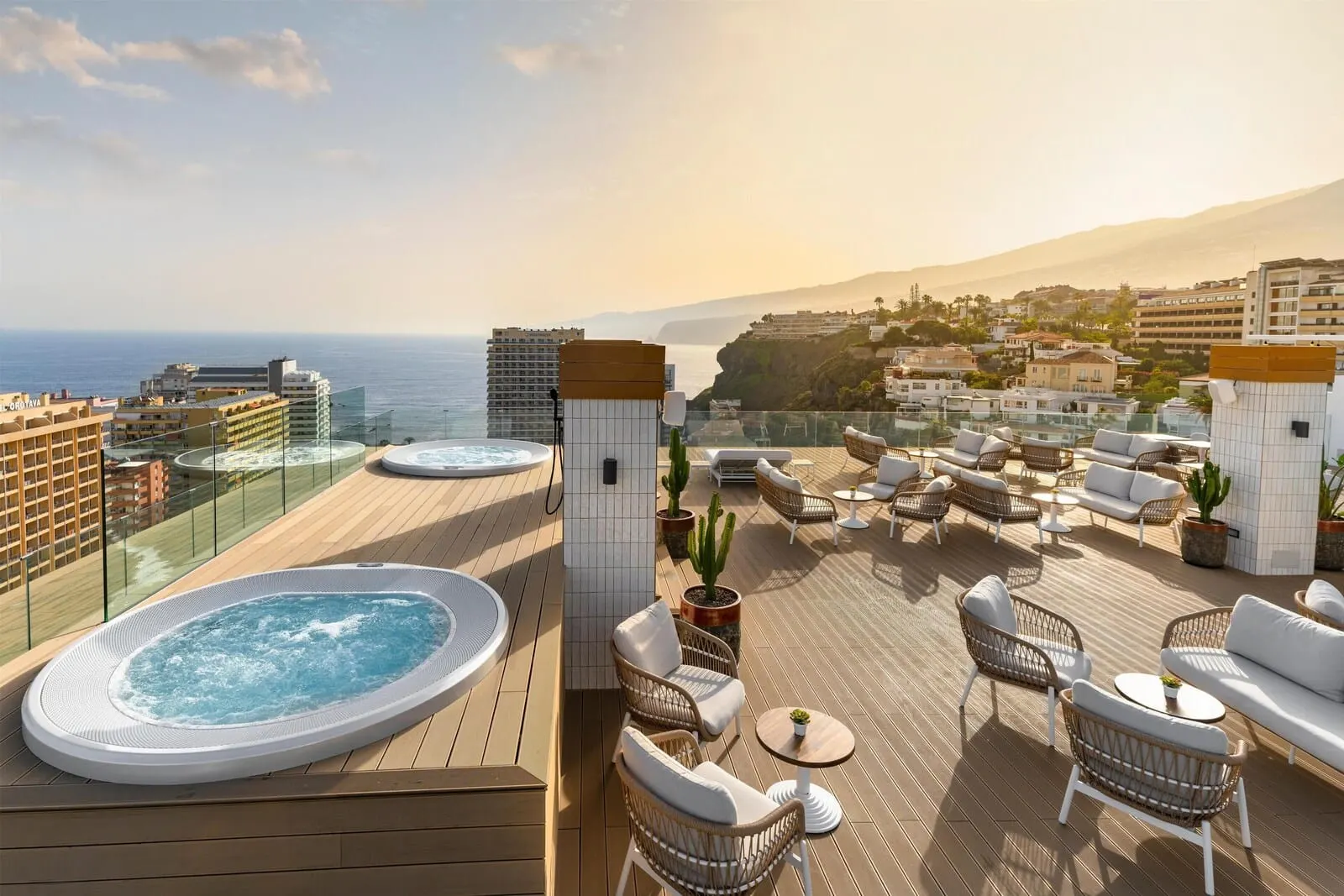 Hotel Atlantic El Tope: A rooftop terrace with a hot tub, wicker furniture, and a view of the sea and cityscape