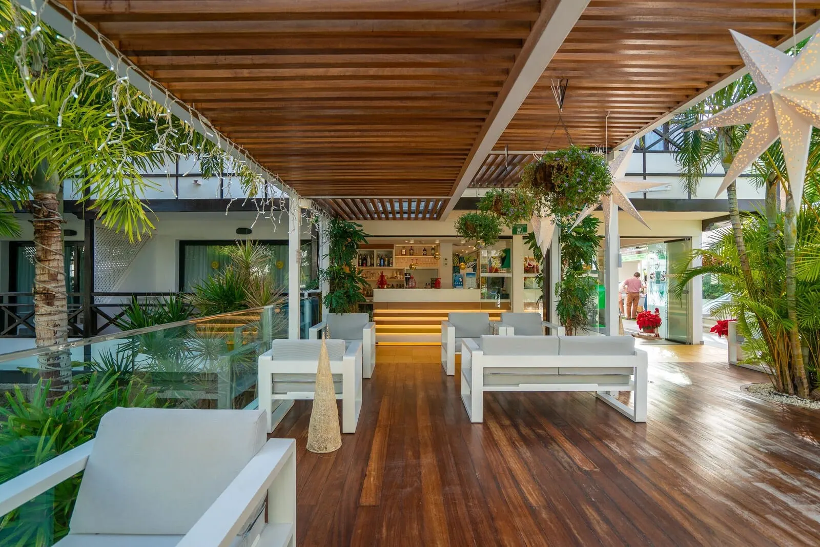 Vanilla Garden Boutique Hotel: A modern indoor space with wooden flooring, white furniture, and green plants