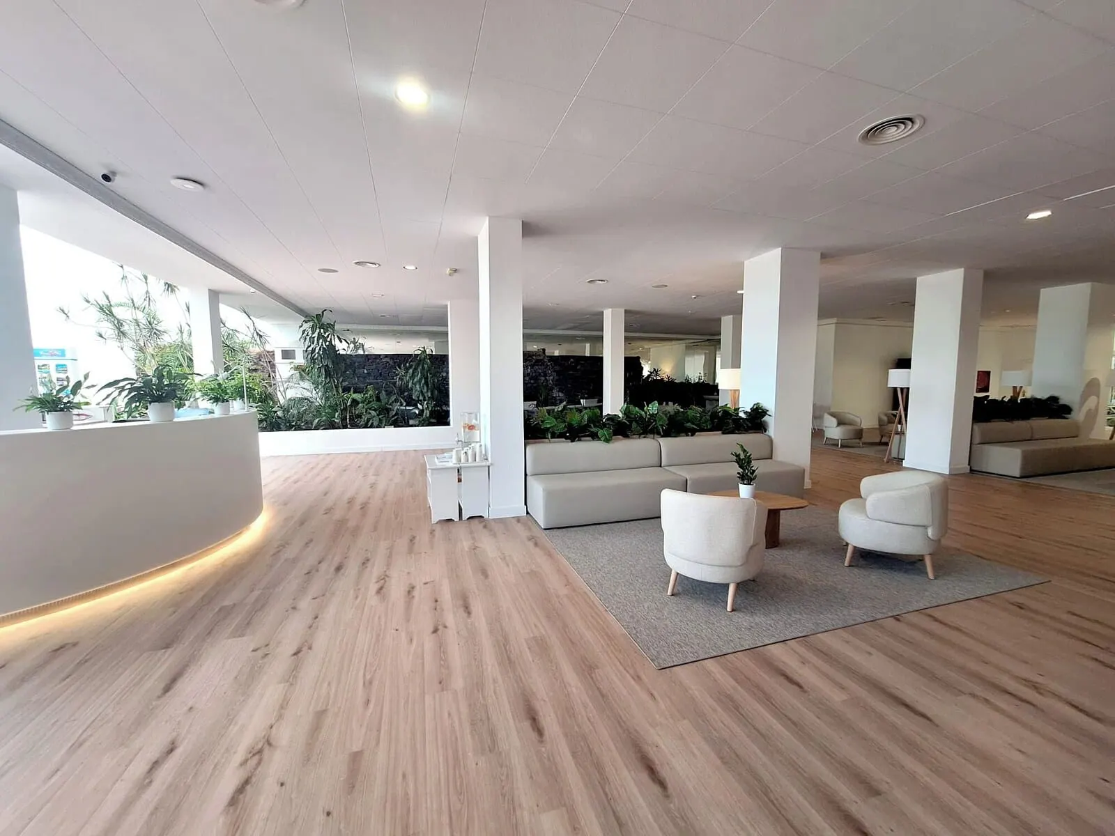 BLUESEA Costa Jardín & Spa: A spacious lobby with a wooden floor, white sofas, and a stone wall backdrop