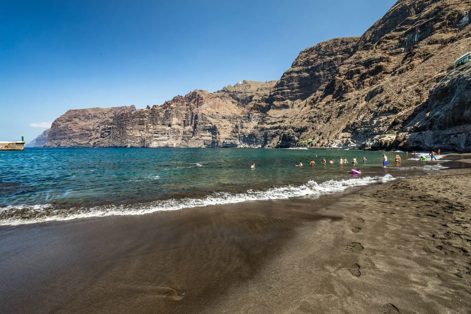 Barceló Santiago: A beach with clear blue water, rocky cliffs, and footprints in the sand