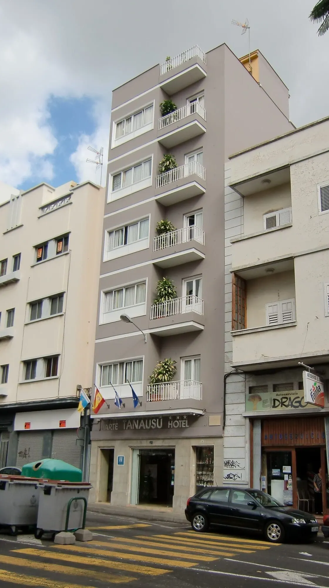 Hotel Tanausú: A multi-story hotel with balconies, a visible entrance, and a parked car in front