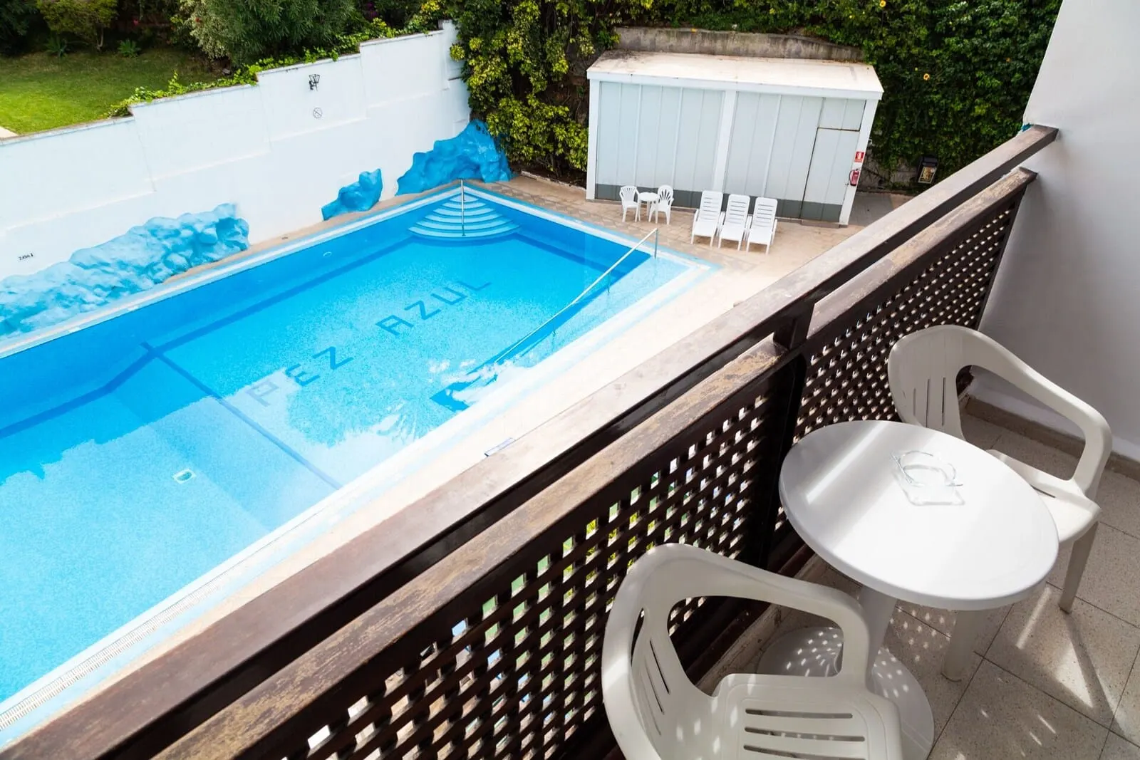Apartamentos Pez Azul: A swimming pool with a blue mosaic design, a hot tub, and a small table with chairs