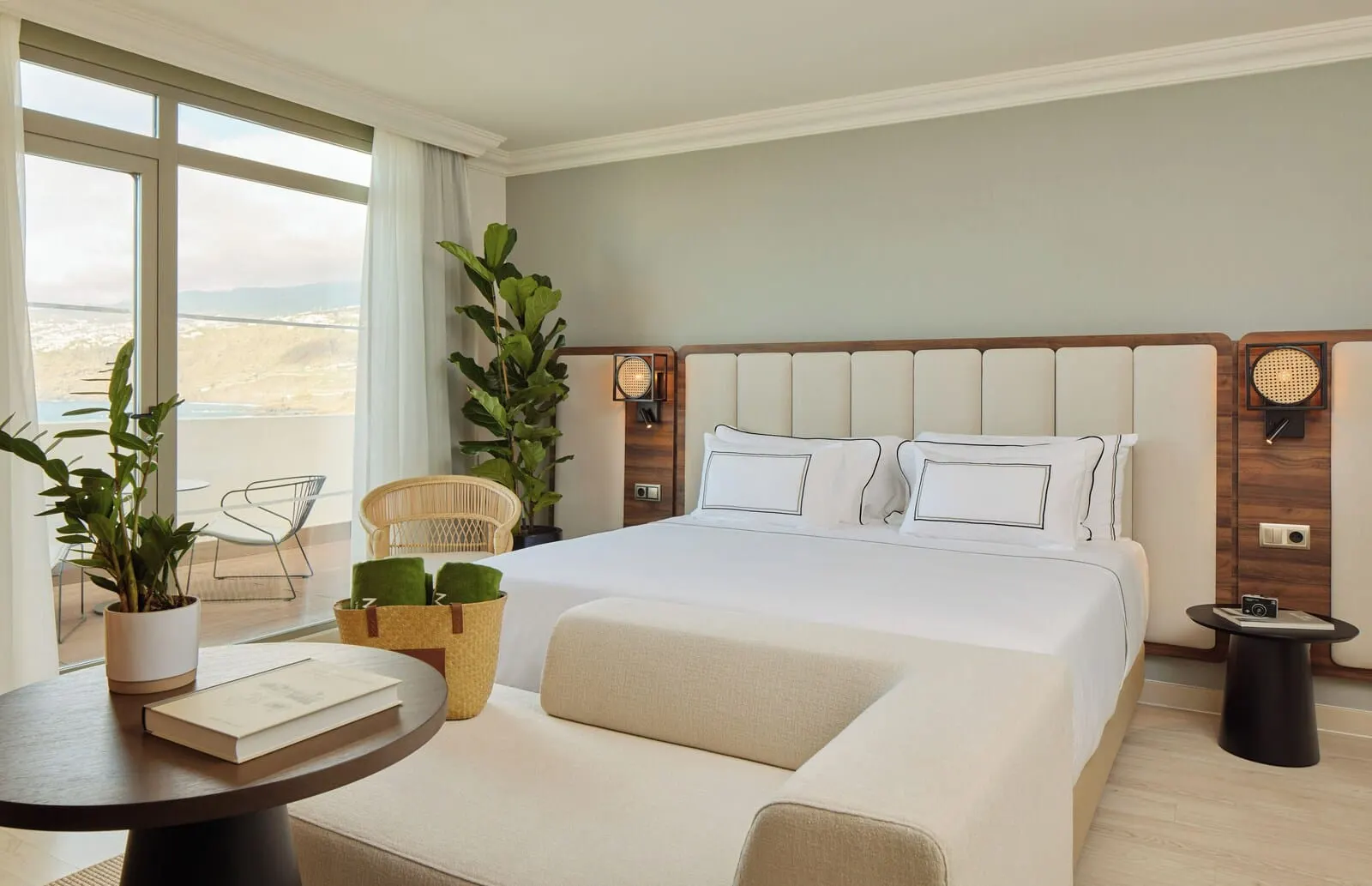 Meliá Costa Atlantis Tenerife: A modern hotel room with a large bed, a round table with a book and a plant, a chair