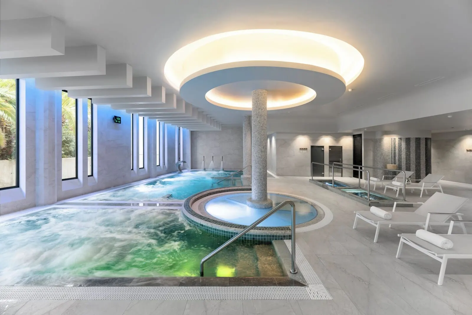 TUI BLUE Atlantic Hills: A modern indoor pool with a central column, surrounded by lounge chairs and a spa area