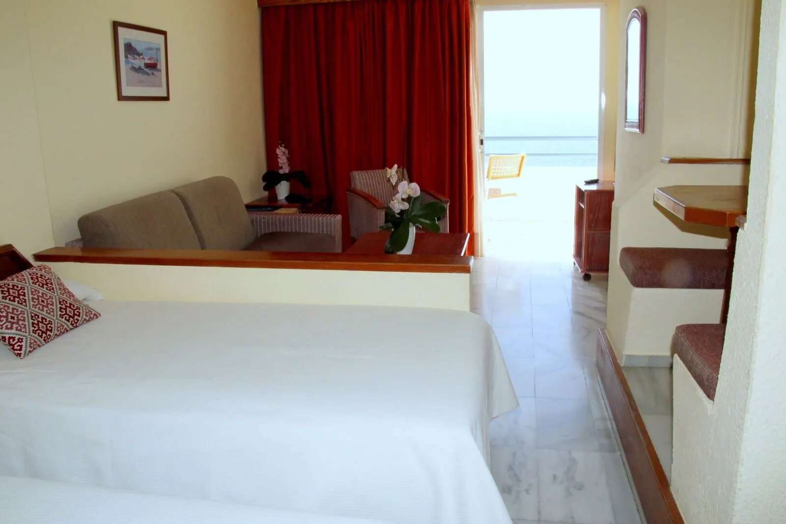 HOVIMA Atlantis: A hotel room with a bed, a sofa, a small table with a vase of flowers