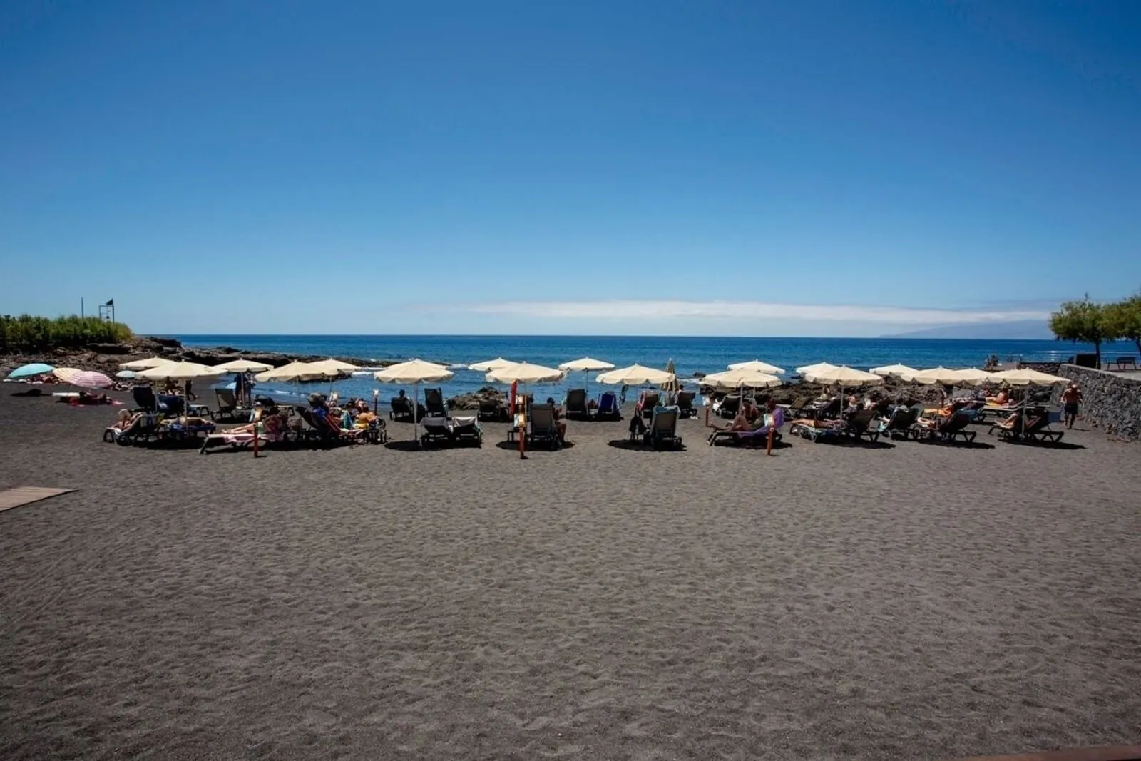 Hotel Rural El Navío: A beach with rows of sun loungers and umbrellas, a clear sky