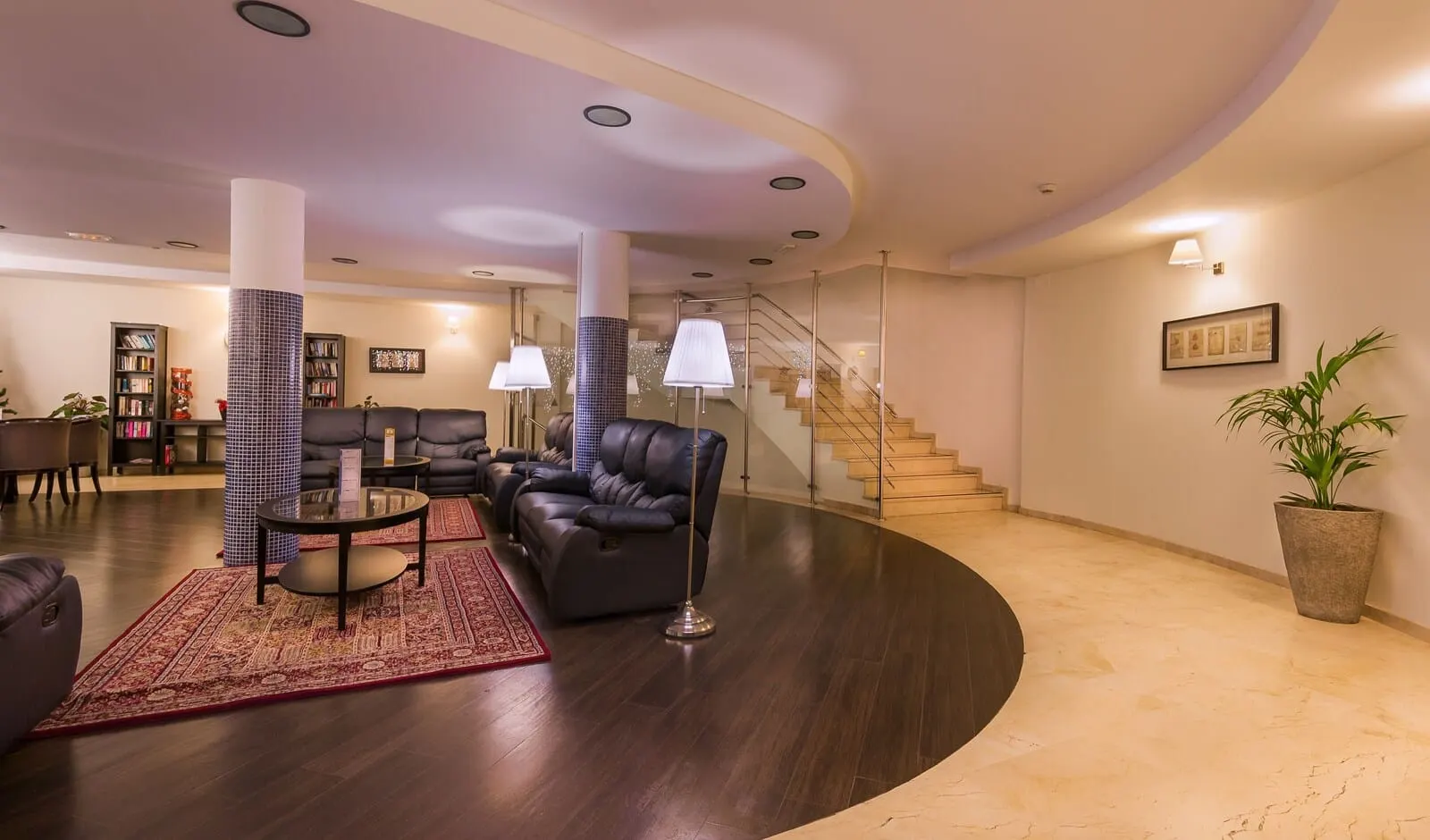 KN Aparthotel Panorámica: A modern living room with a curved ceiling, dark wood flooring, leather sofas