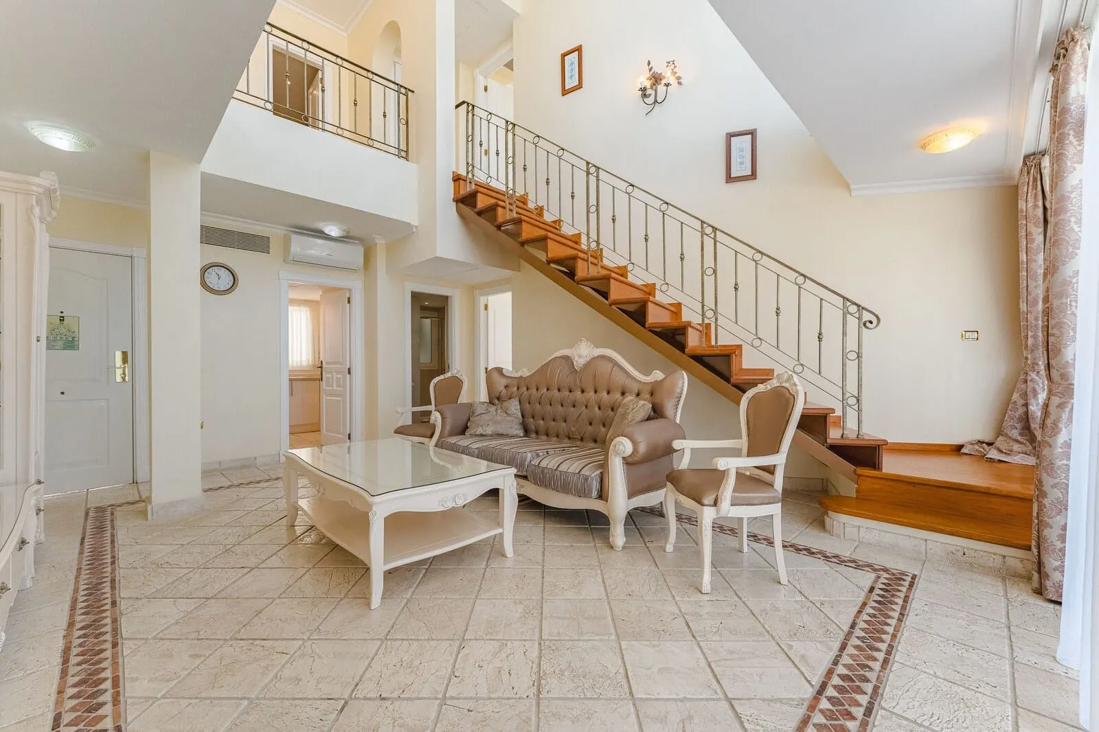 Flamingo Suites Boutique Hotel: A spacious living area with a high ceiling, a staircase, a sofa, and a coffee table