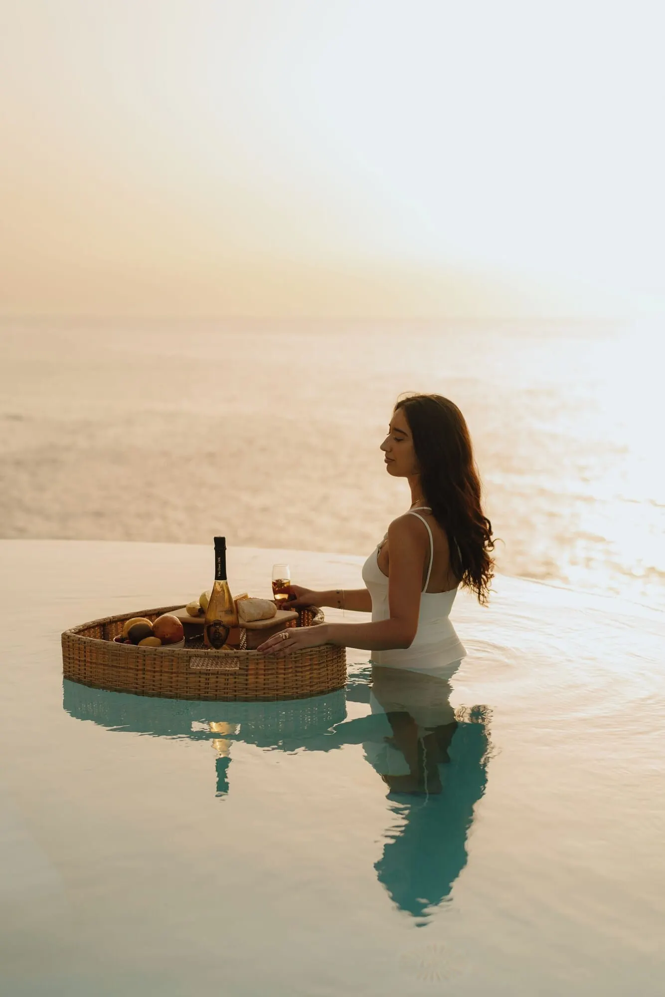 Costa Mágica Boutique Hotel: A woman sitting by a pool with a basket of food and drinks