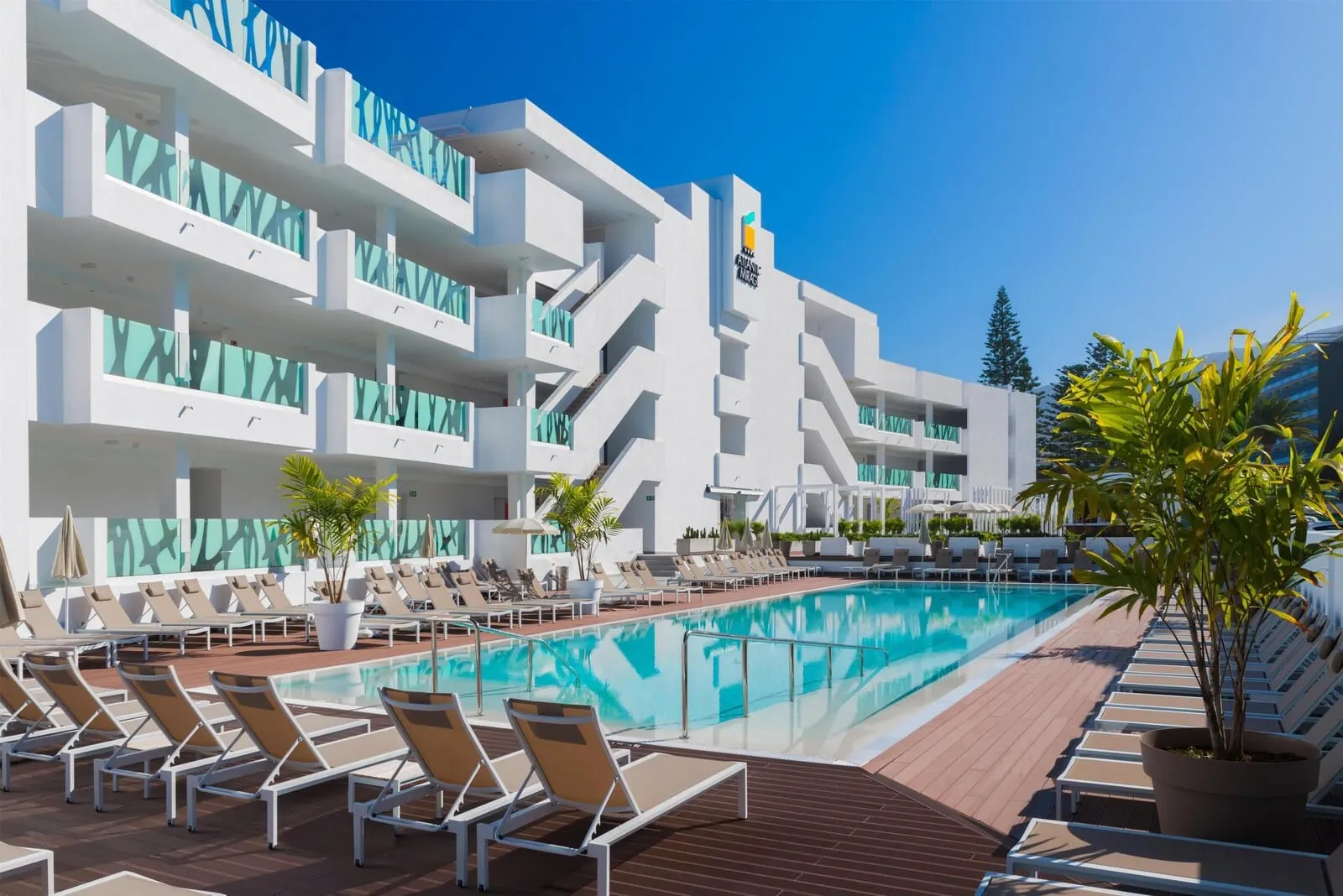Atlantic Mirage Suites & Spa: A modern hotel with a swimming pool, sun loungers, and a clear blue sky