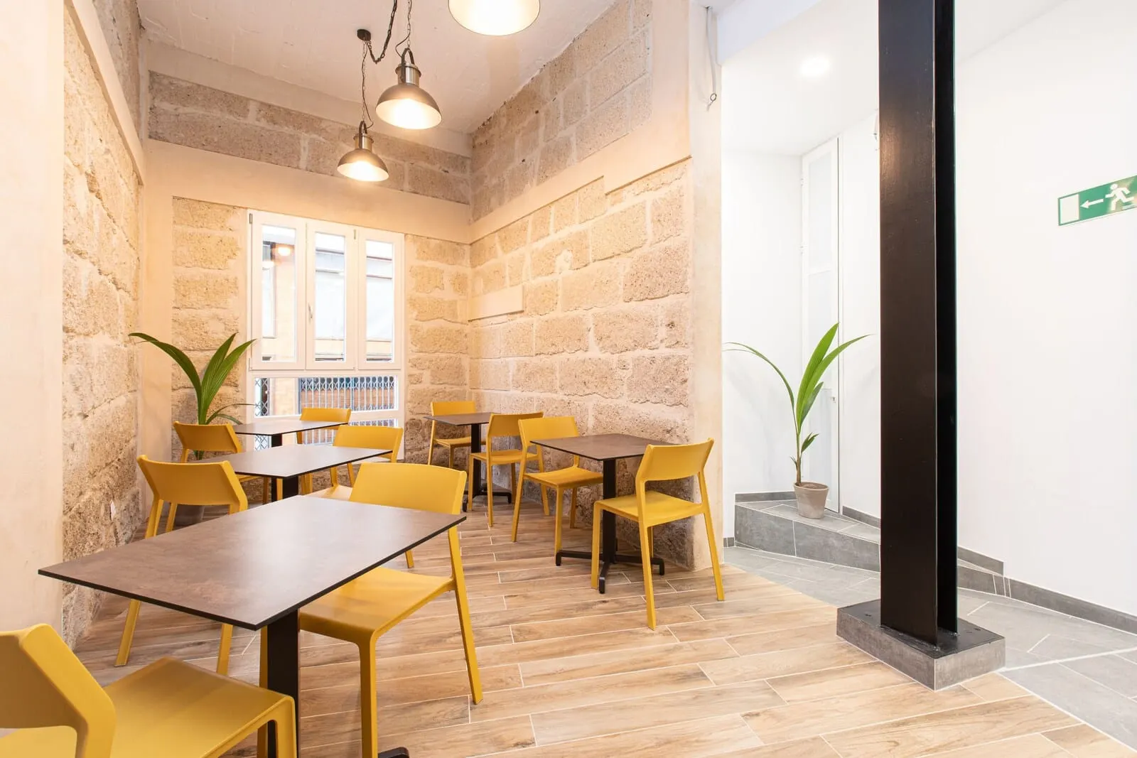 Suncanarias Hotel Adeje Plaza: A dining area with wooden tables and yellow chairs, stone walls, and potted plants