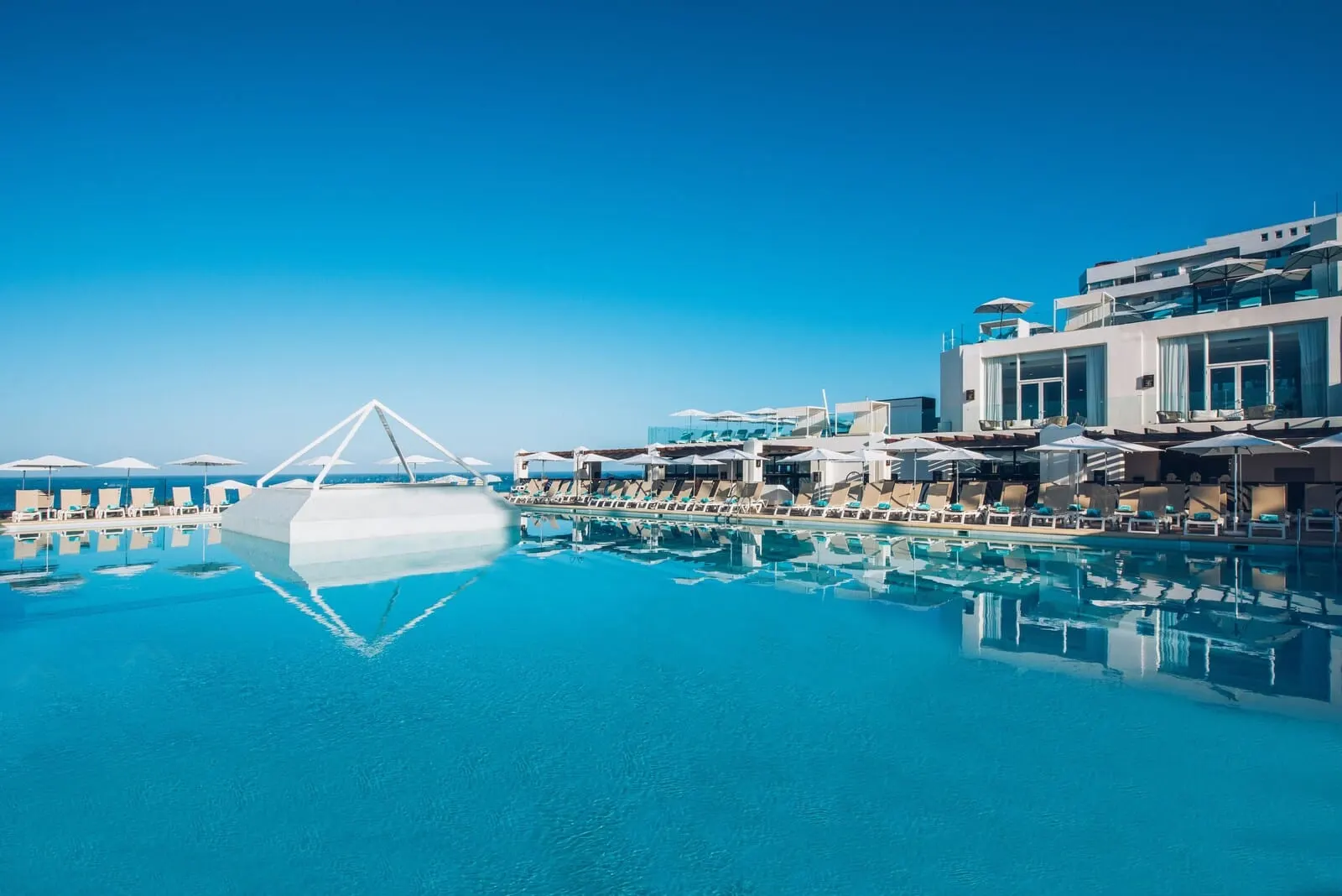 Iberostar Waves Bouganville Playa: A modern hotel with a large infinity pool, sun loungers, and a clear view of the ocean