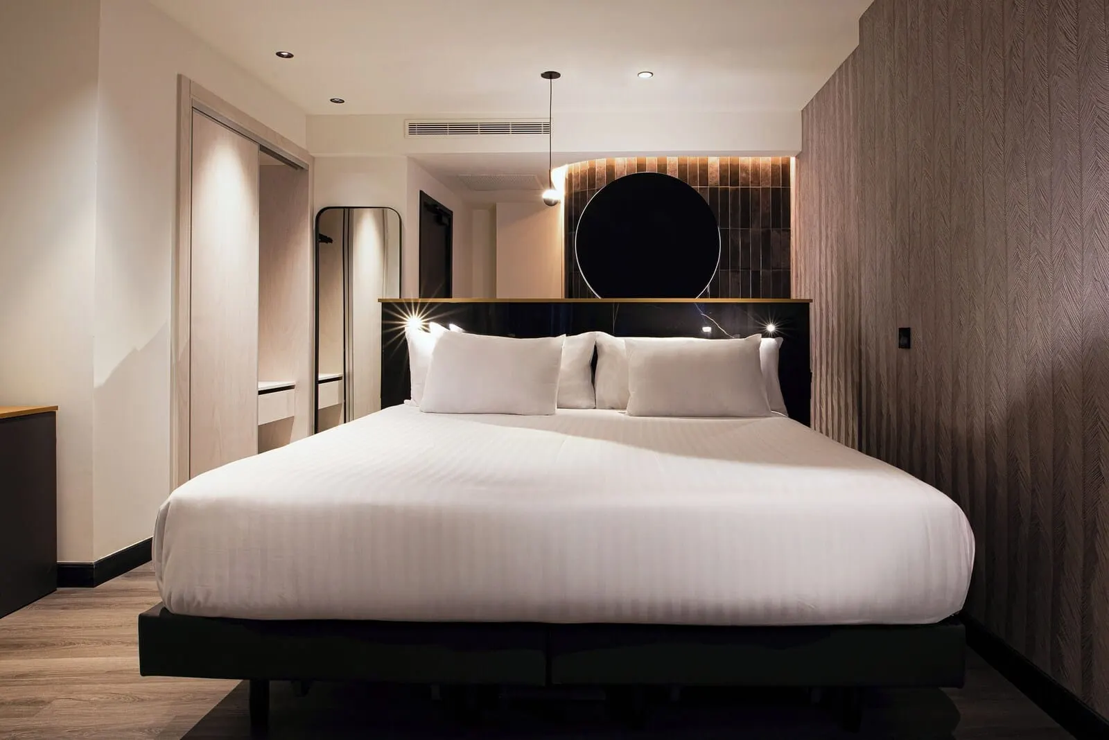 Silken Saaj Maar: A modern hotel room with a large bed, a round mirror above the bed