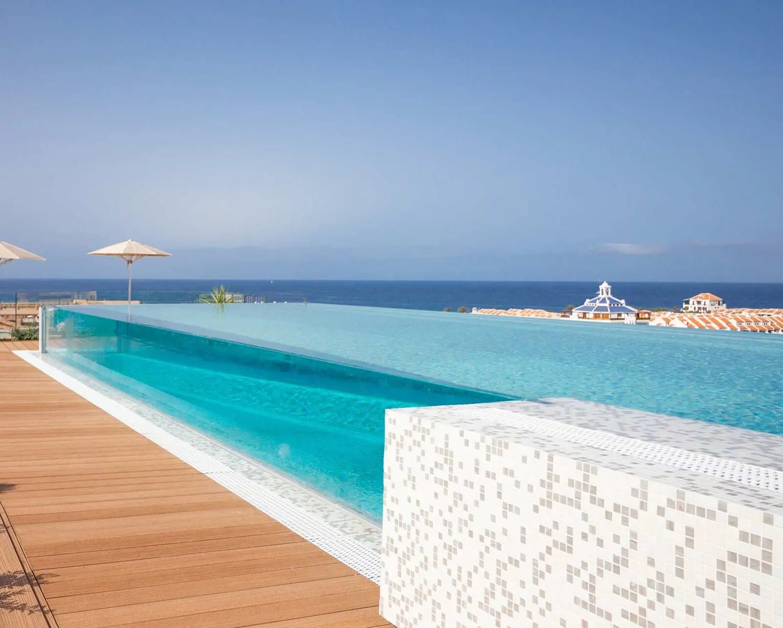 Spring Hotel Vulcano: A infinity pool with a wooden deck and a white tiled wall