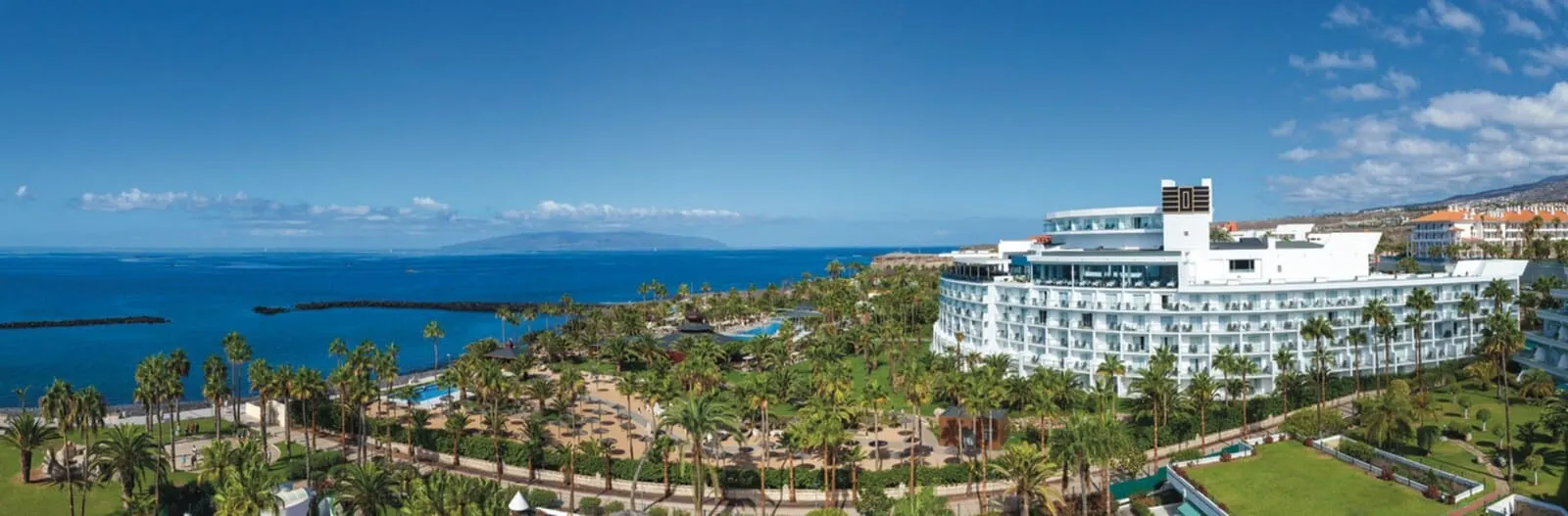 Hotel Riu Palace Tenerife: A resort with a circular building, a pool, and palm trees