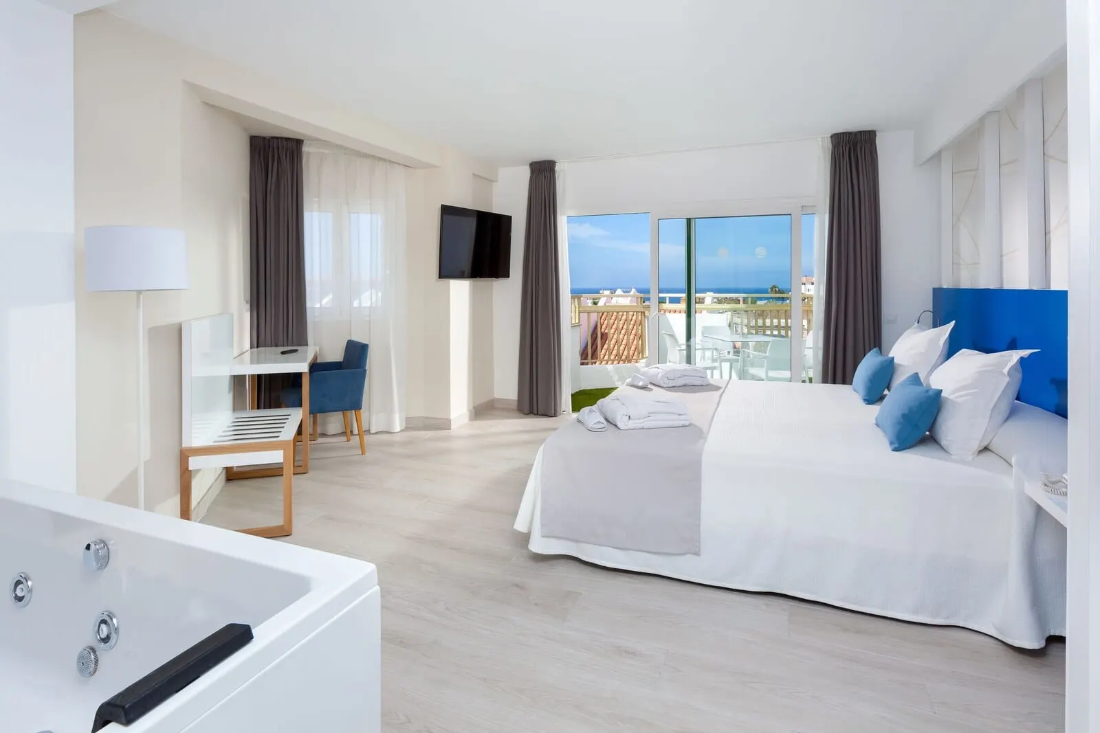 Playaolid Suites & Apartments: A modern hotel room with a large bed, a desk, and a TV
