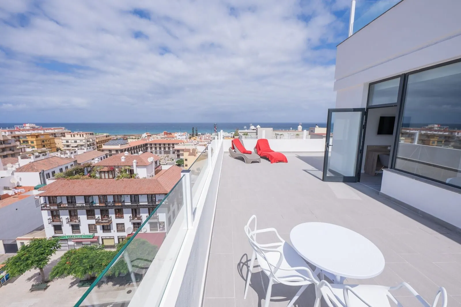 AF Valle Orotava Hotel: A rooftop terrace with a table and chairs, red lounge chairs