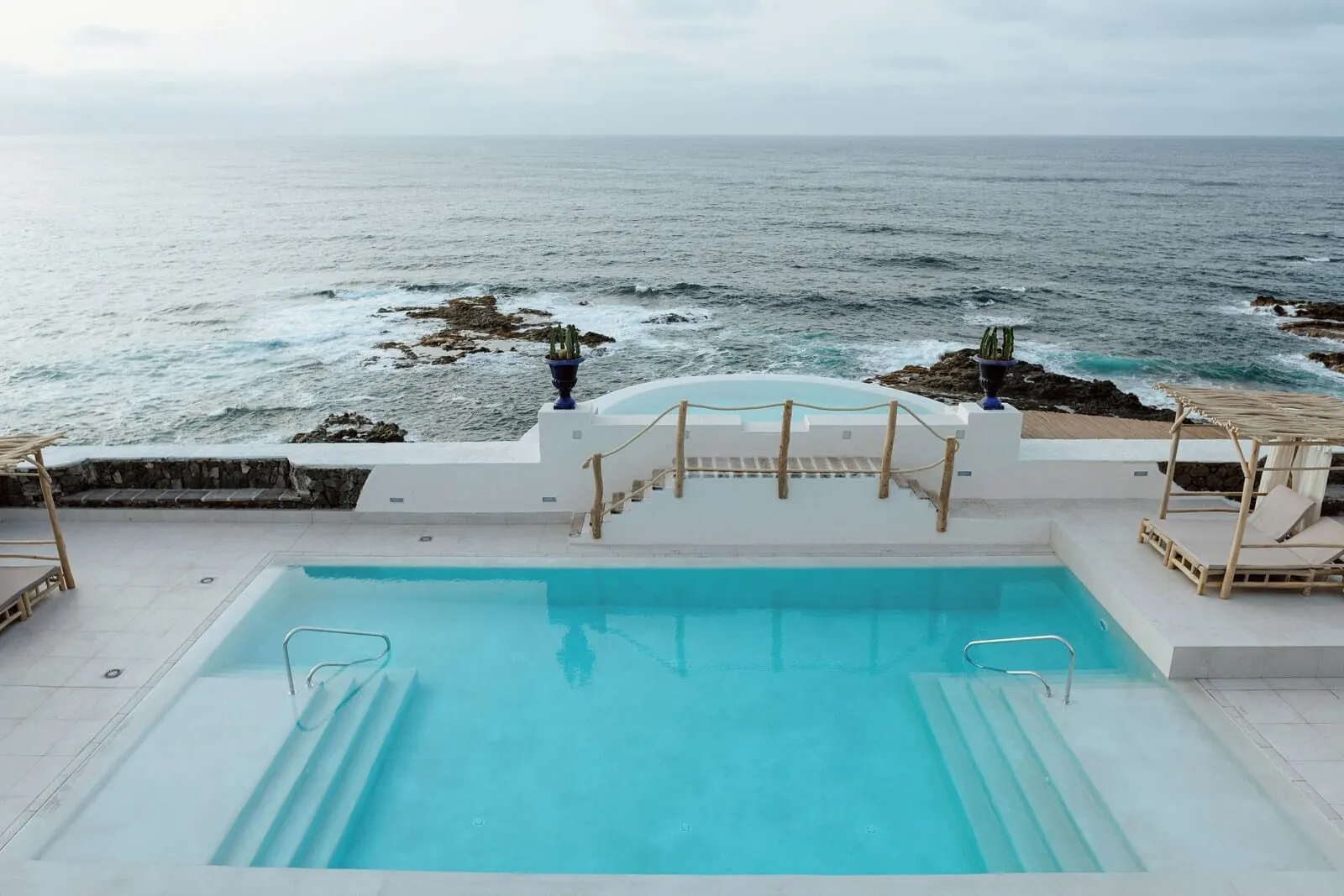 Costa Mágica Boutique Hotel: A pool with a view of the ocean, wooden deck, and lounge chairs