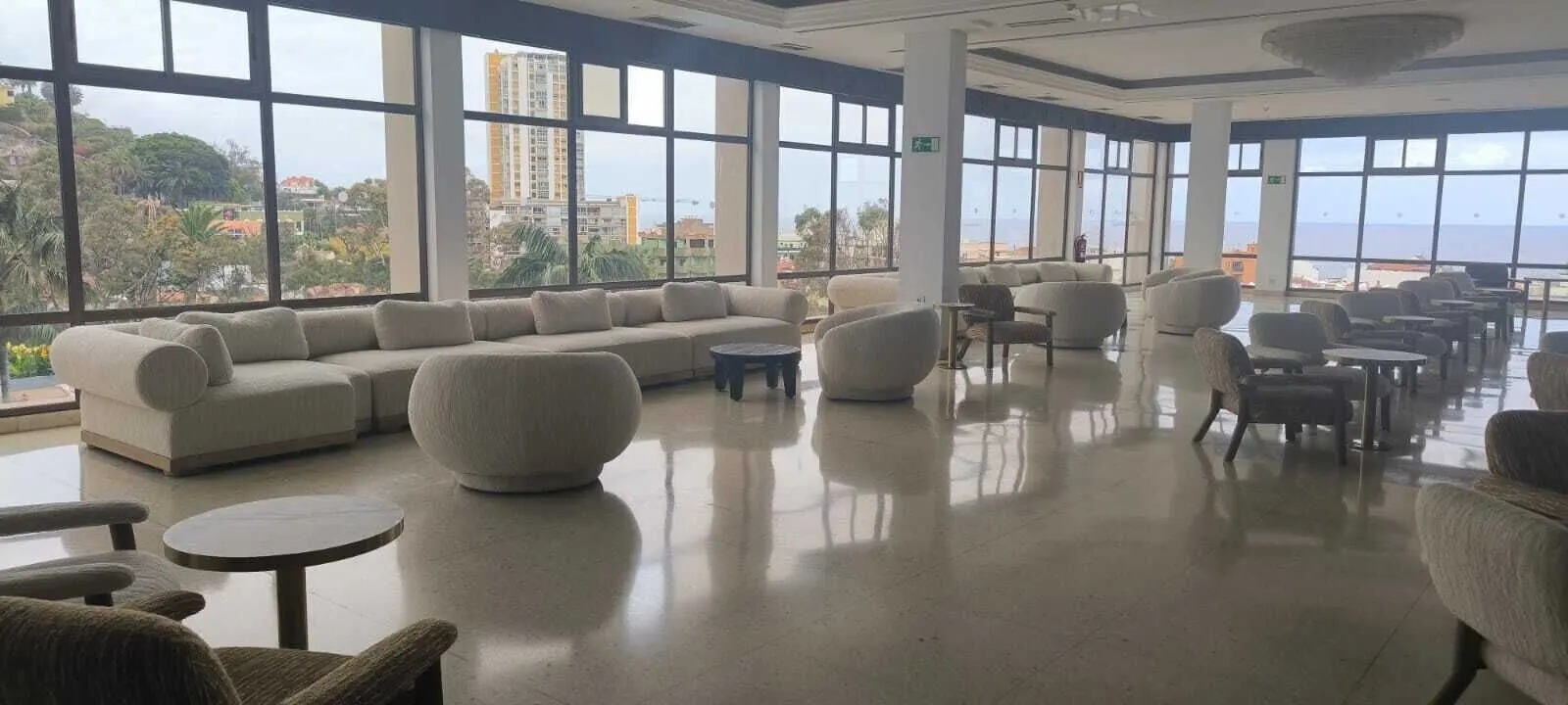 Hotel Atlantic El Tope: A spacious indoor area with large windows, a sectional sofa, and multiple chairs