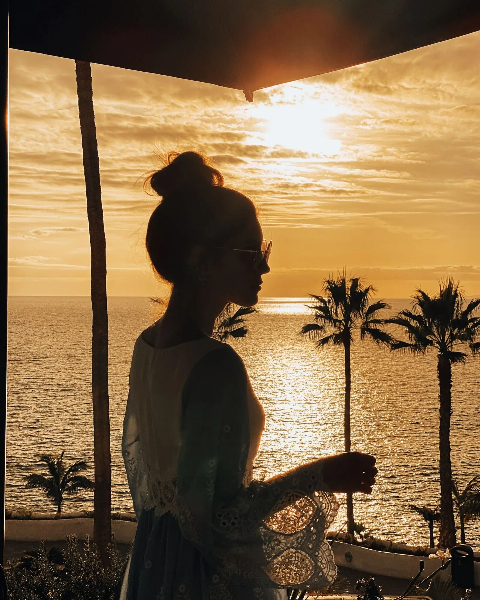 Hyatt Ziva Jardín Tropical Tenerife: A person standing by a window overlooking a sunset over the ocean