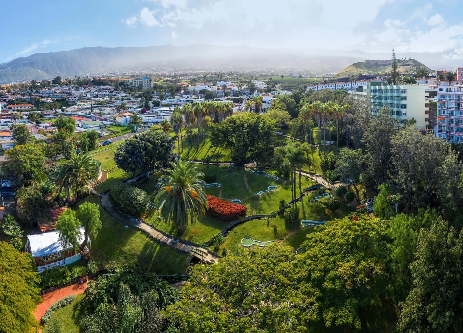 Parque Vacacional Eden: A residential area with a park featuring walking paths, palm trees, and a small pond