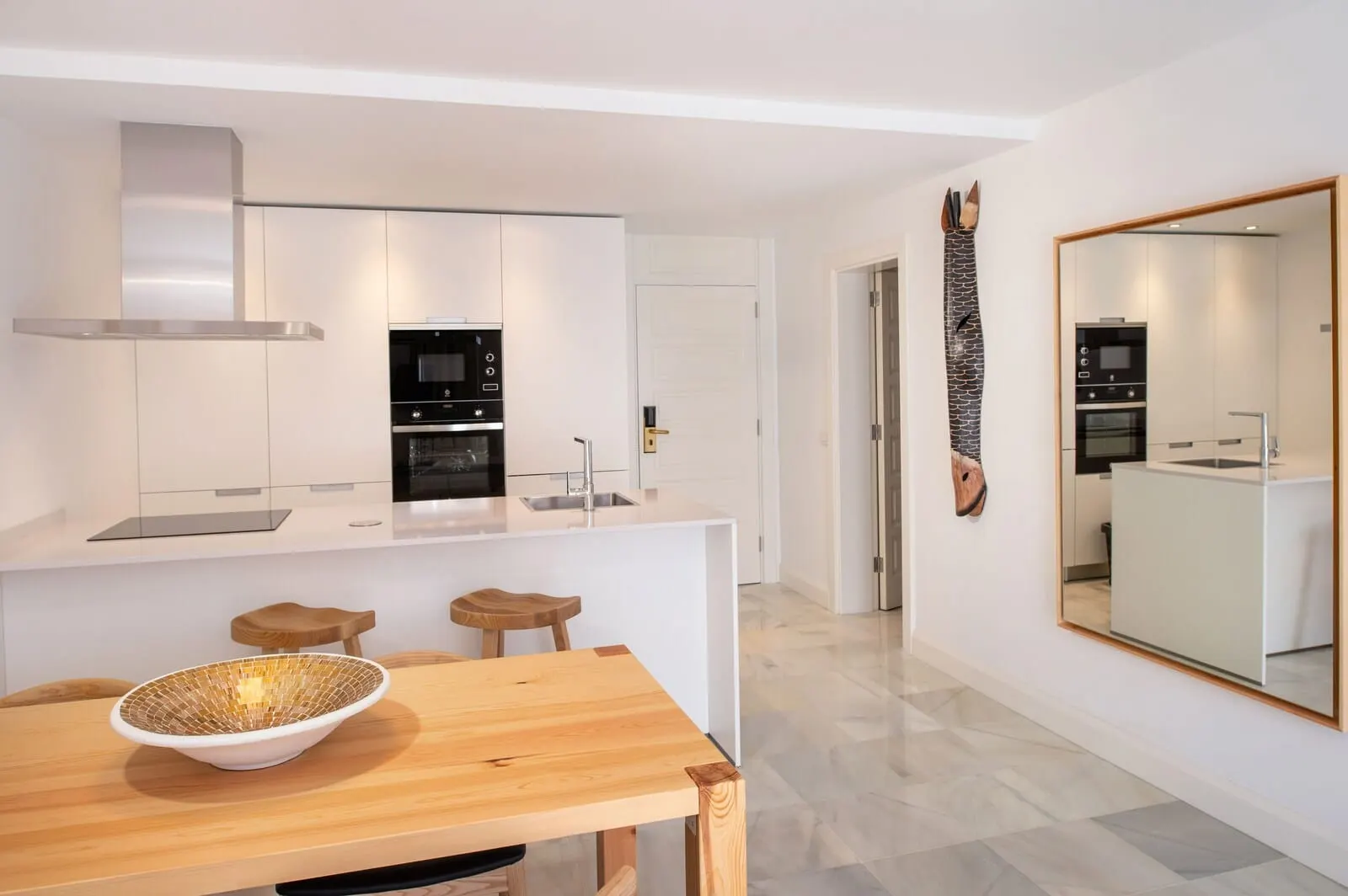 Parque Santiago IV: A modern kitchen with white cabinetry, a central island with stools