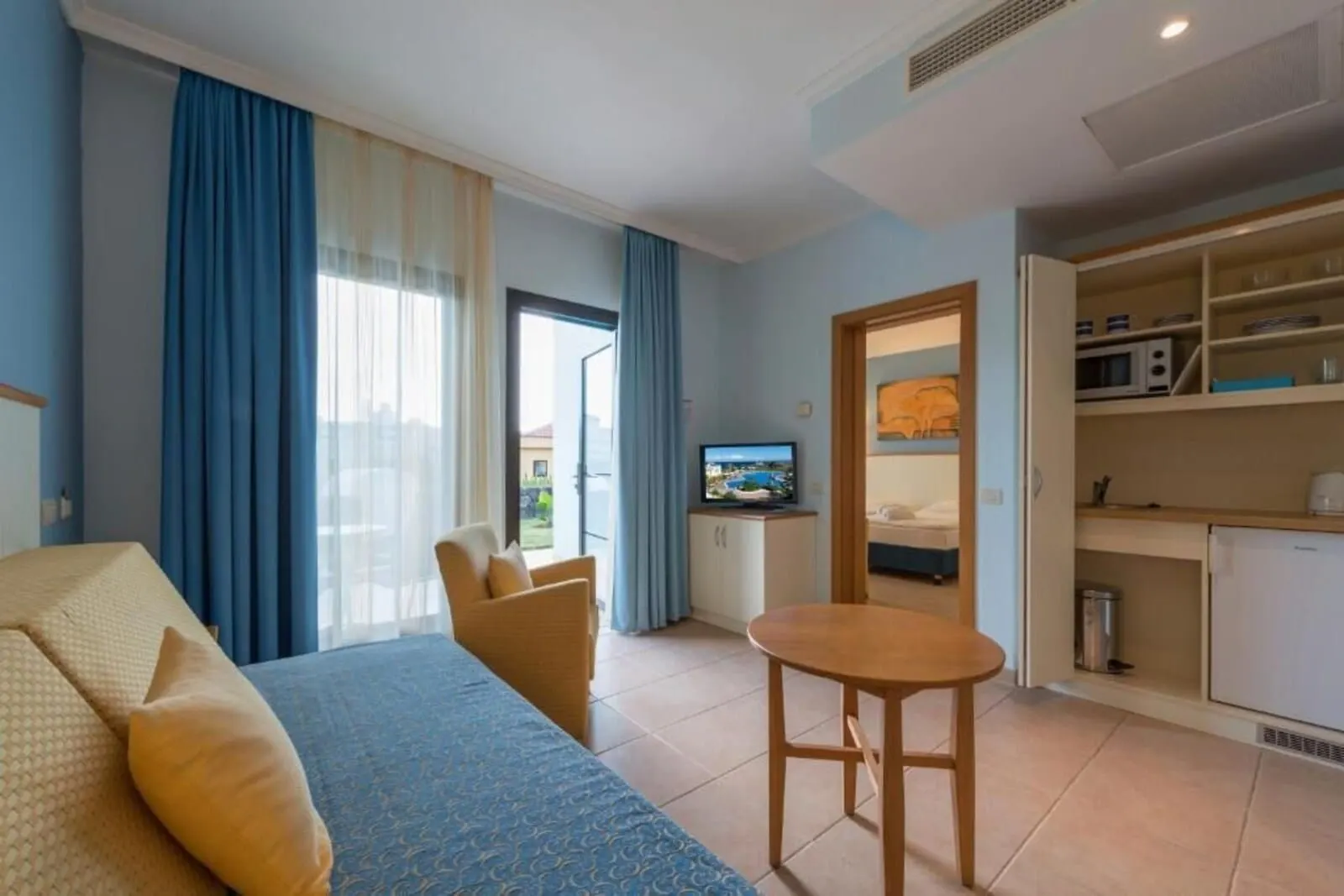 Hotel Luz del Mar: A hotel room with a bed, a small table, a TV, and a kitchenette