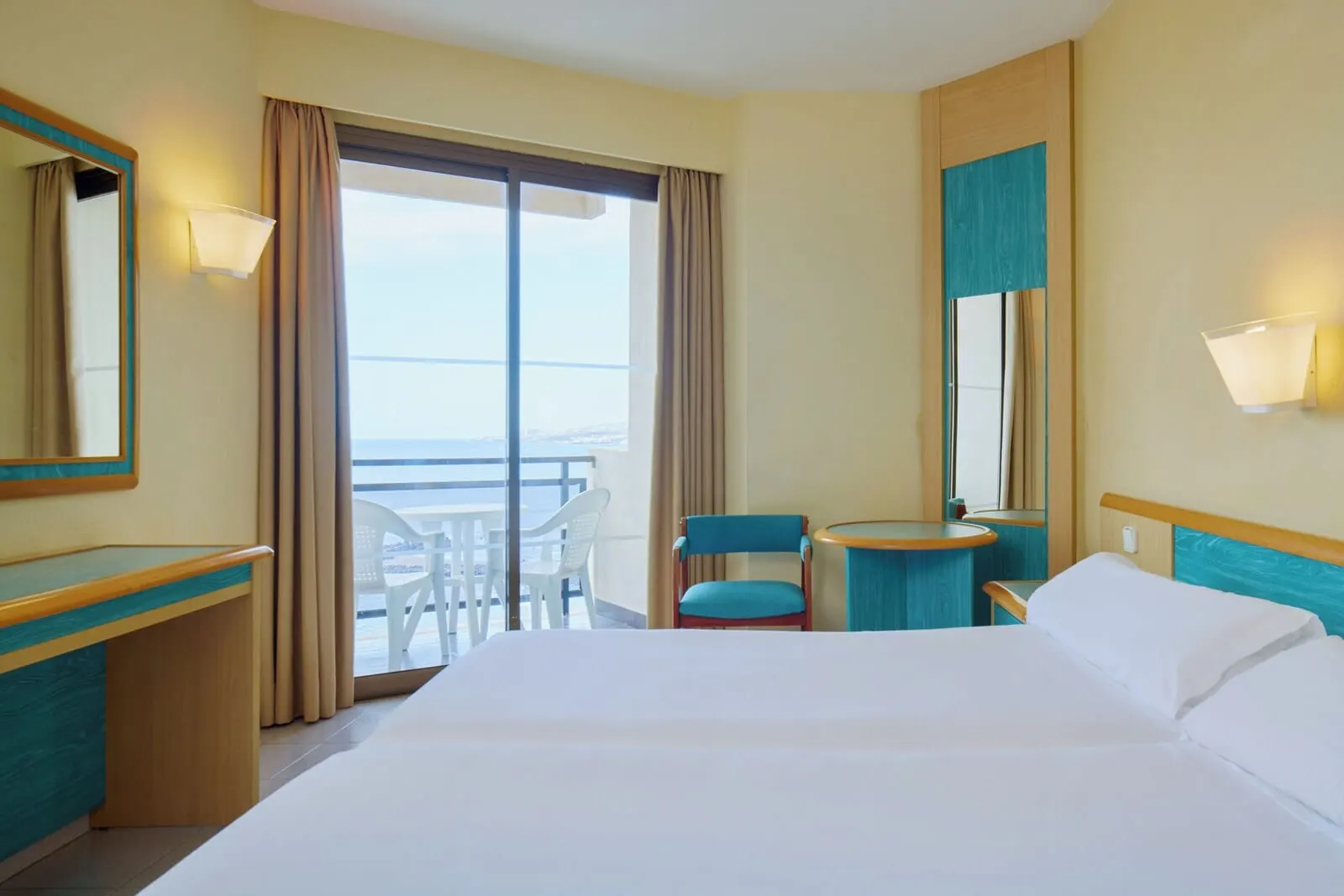 Sol Tenerife: A hotel room with a bed, a desk, a chair, a small table, and a balcony with a view