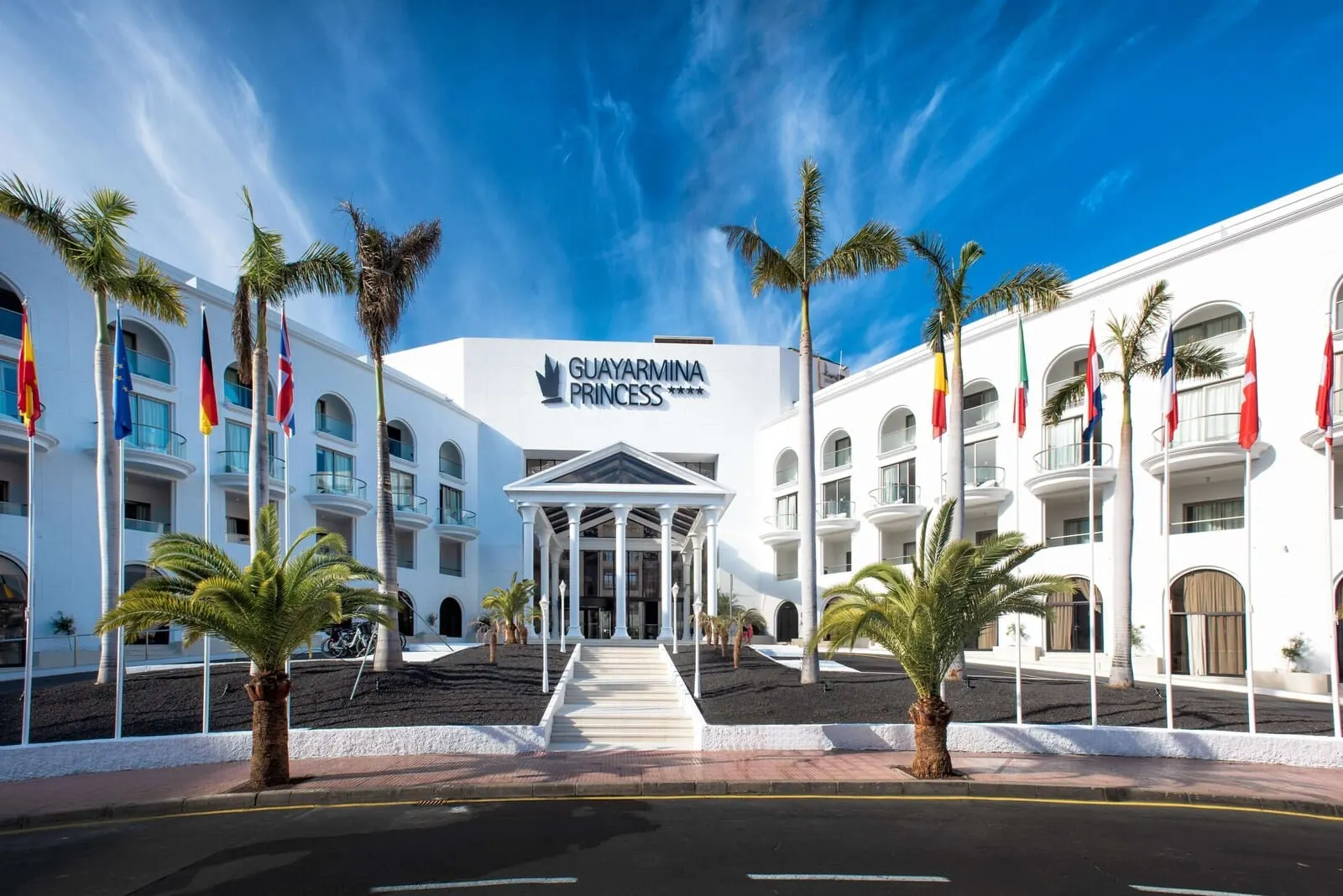 Guayarmina Princess: A hotel with a central entrance, palm trees, and multiple balconies