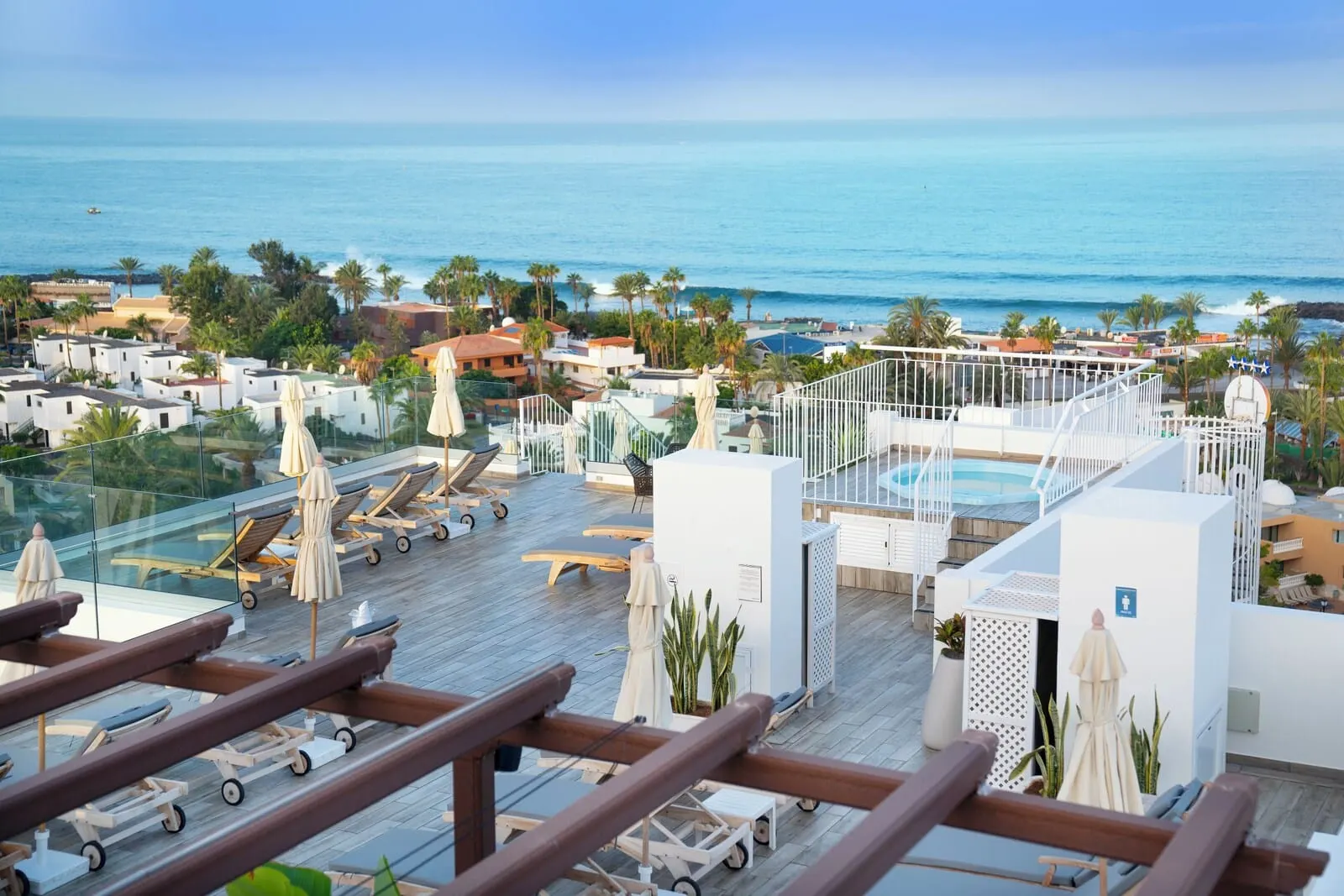 Coral Ocean View: A rooftop pool area with sun loungers, umbrellas, and a view of the ocean