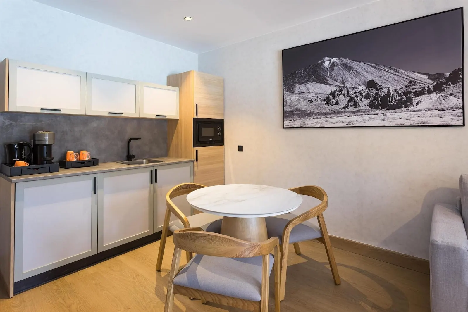 Radisson Resort & Residences Tenerife: A modern kitchen with a dining area, wooden cabinets, a round table
