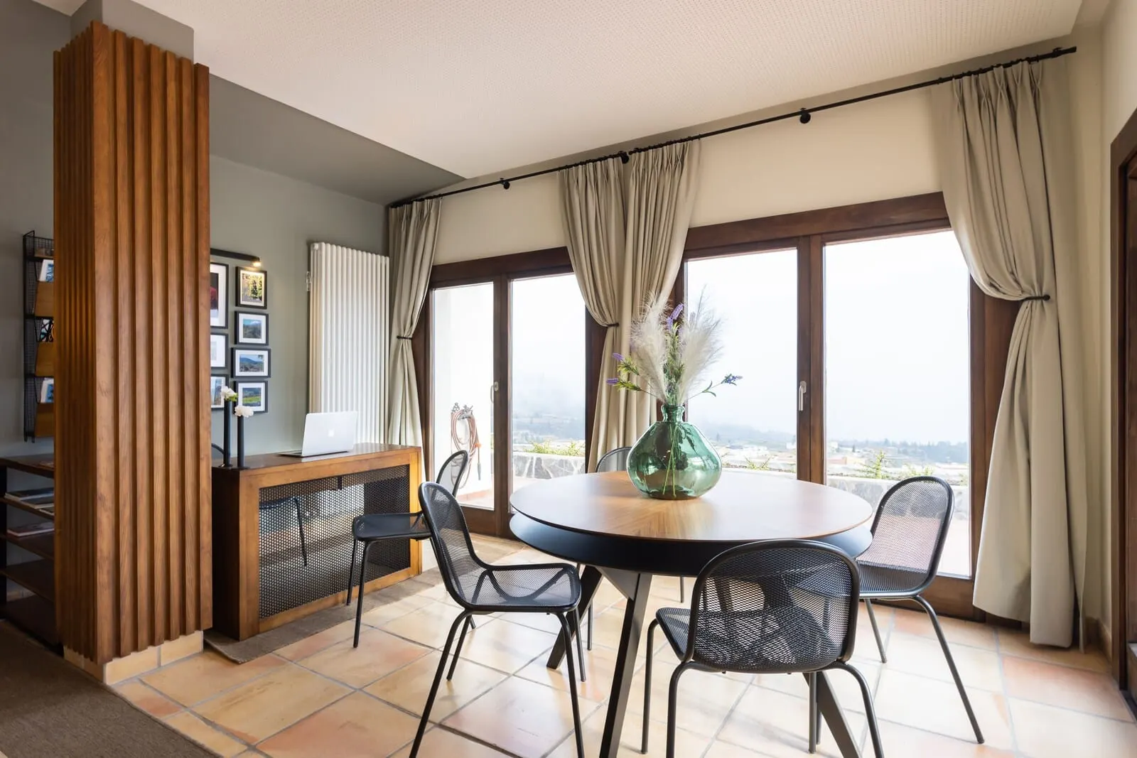 Hotel Alta Montaña: A modern dining area with a round table, four chairs, a laptop on a wooden desk