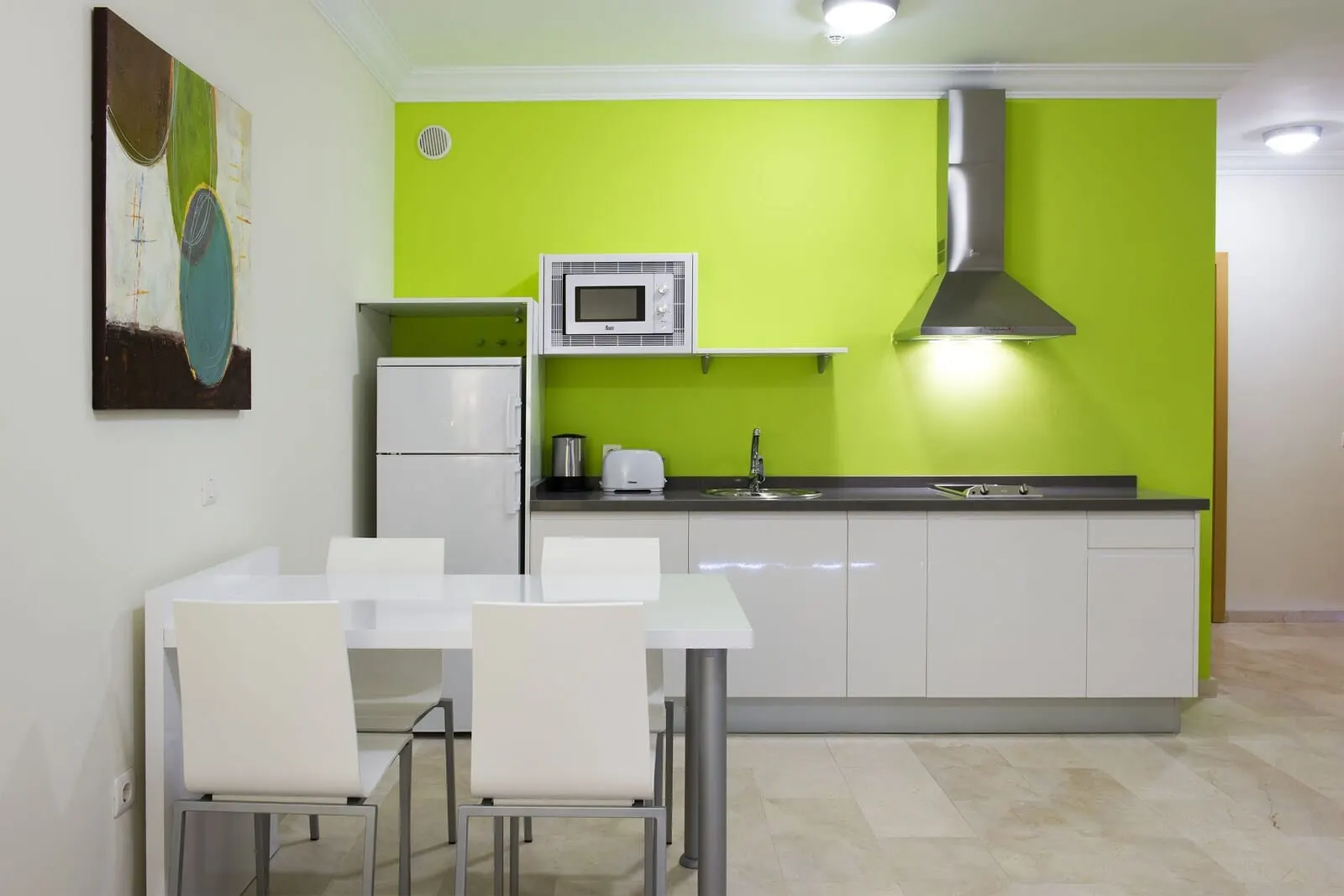 KN Aparthotel Panorámica: A modern kitchen with white cabinets, a green accent wall, a microwave