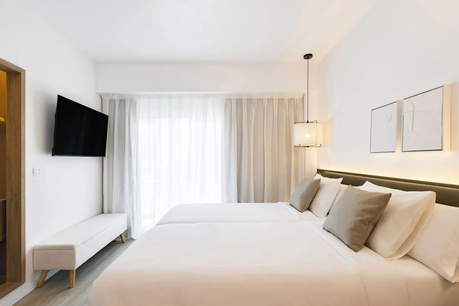 Adonis La Suite: A hotel room with a large bed, a bench, a flat-screen TV