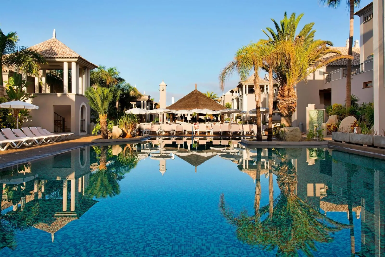Marylanza Suites & Spa: A resort pool with a reflection of palm trees and a gazebo