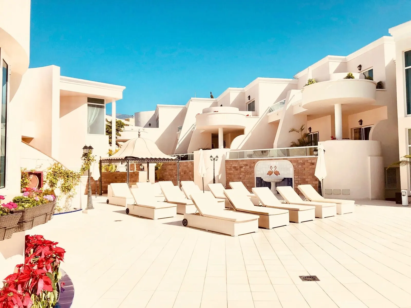 Flamingo Suites Boutique Hotel: A resort with white buildings, a pool area with sun loungers, and a fountain