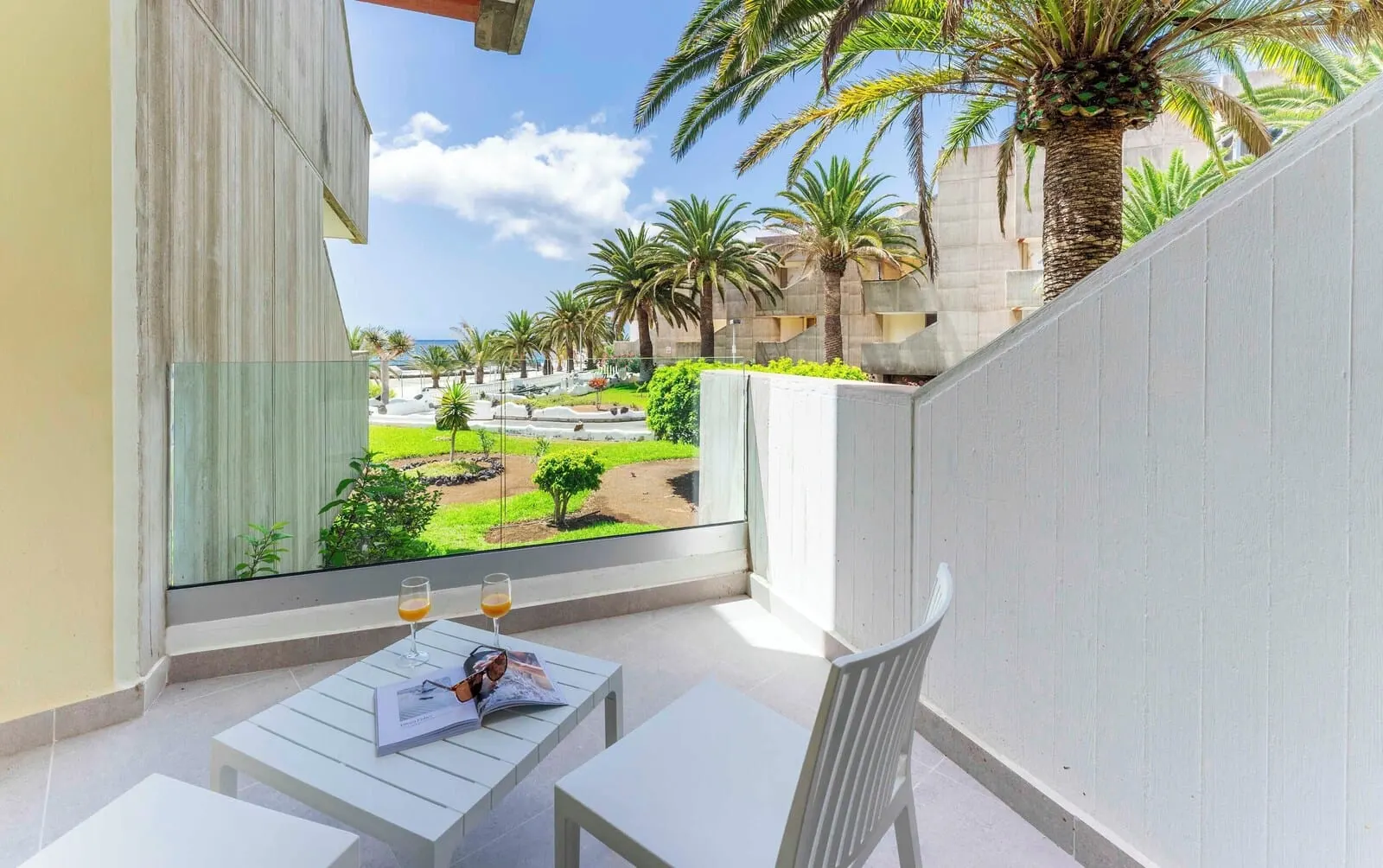 Ona Alborada: A balcony with a view of a landscaped garden, palm trees