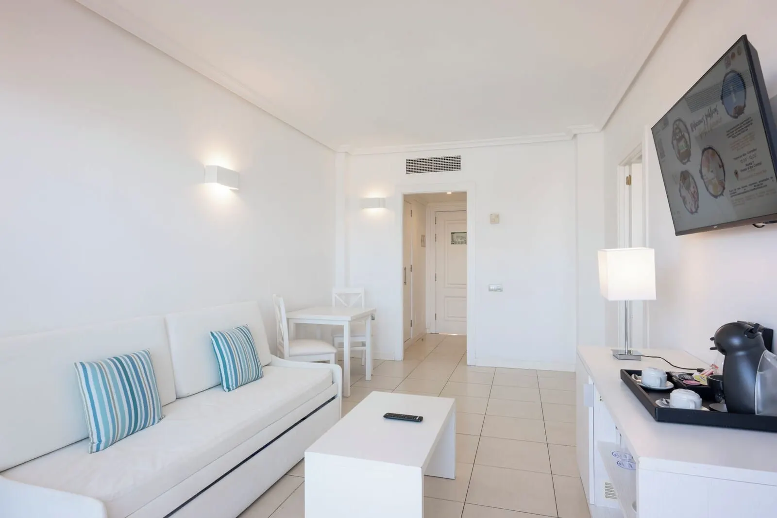 Landmar Costa Los Gigantes: A modern, well-lit living room with a sofa, coffee table, and a dining area