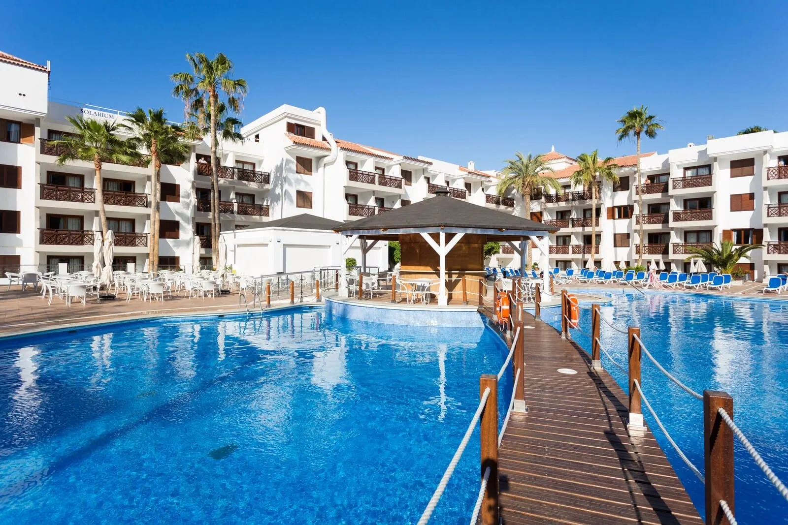 Globales Tamaimo Tropical: A hotel pool area with a wooden deck, lounge chairs, and palm trees