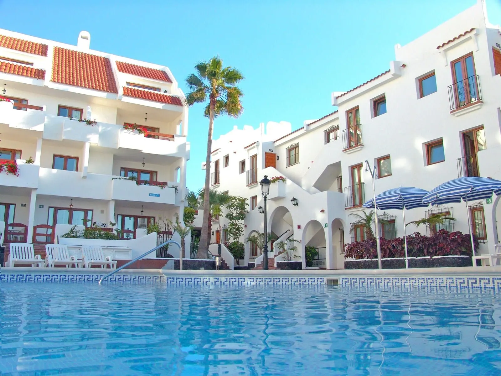 Ona Beverly Hills Suites: A hotel with a pool, white buildings, red-tiled roofs, and balconies with plants