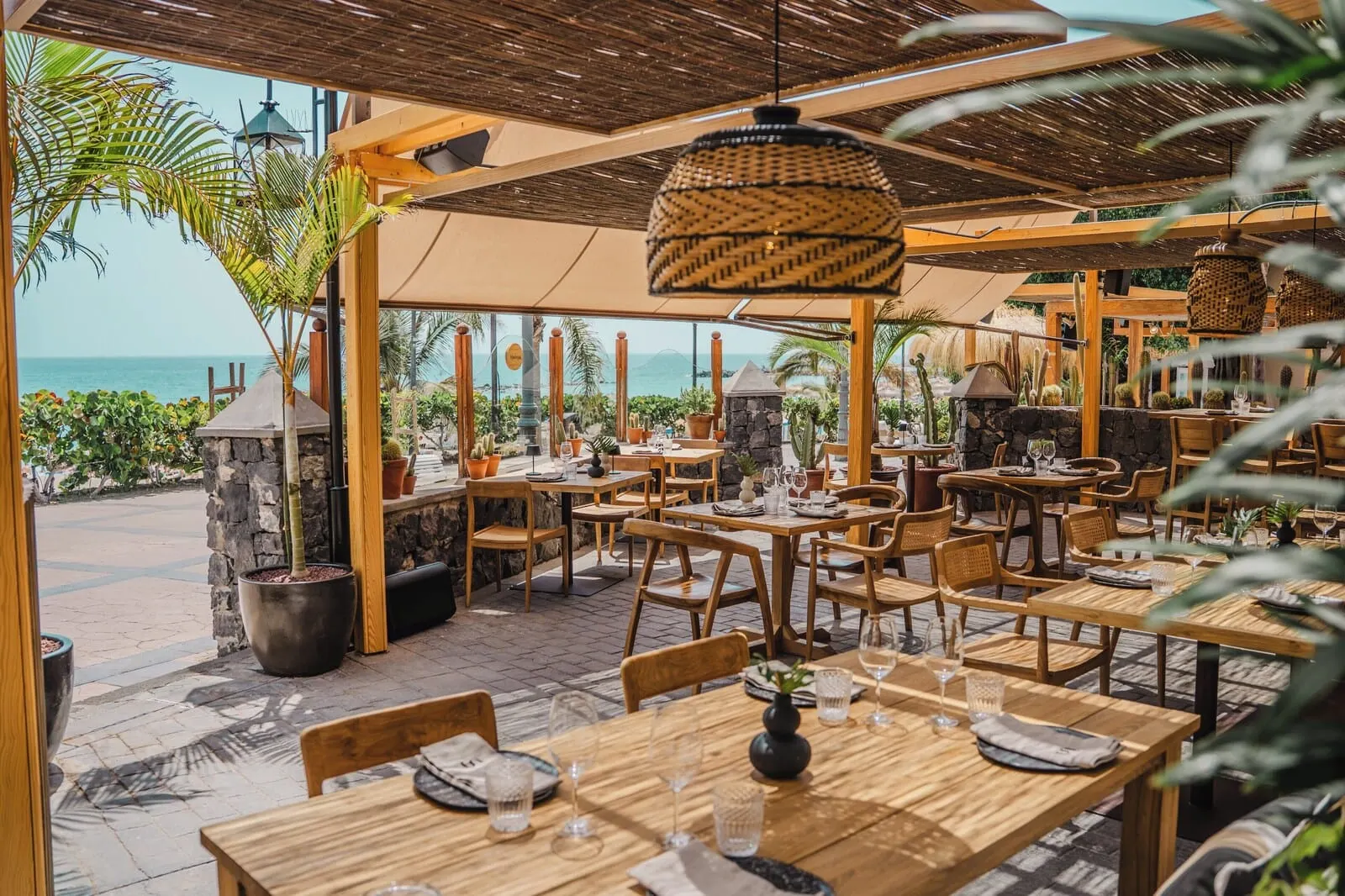 Bahía del Duque: An outdoor restaurant with wooden tables and chairs, potted plants