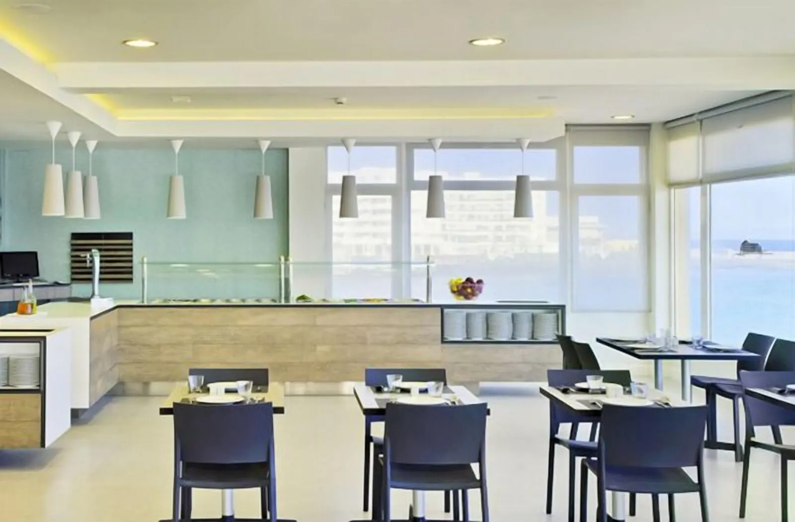Médano Hotel: A modern restaurant with a central counter, dining tables, and chairs