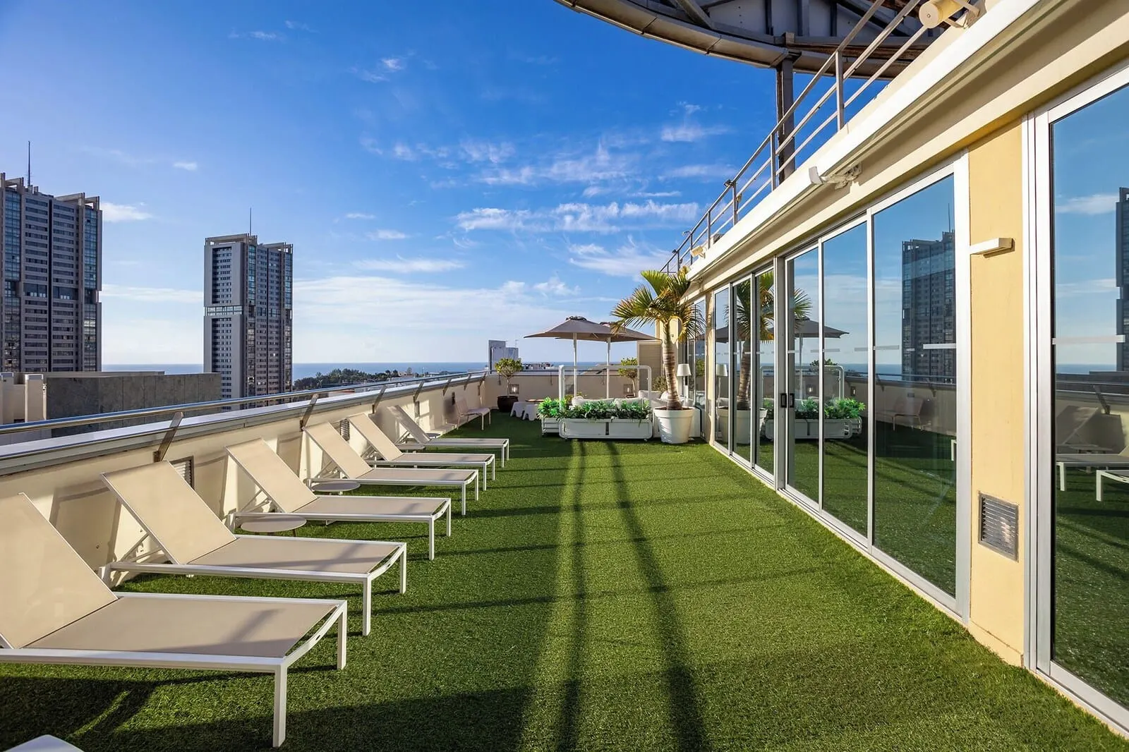 Eurostars Atlántida: A rooftop terrace with sun loungers, a small table, and potted plants