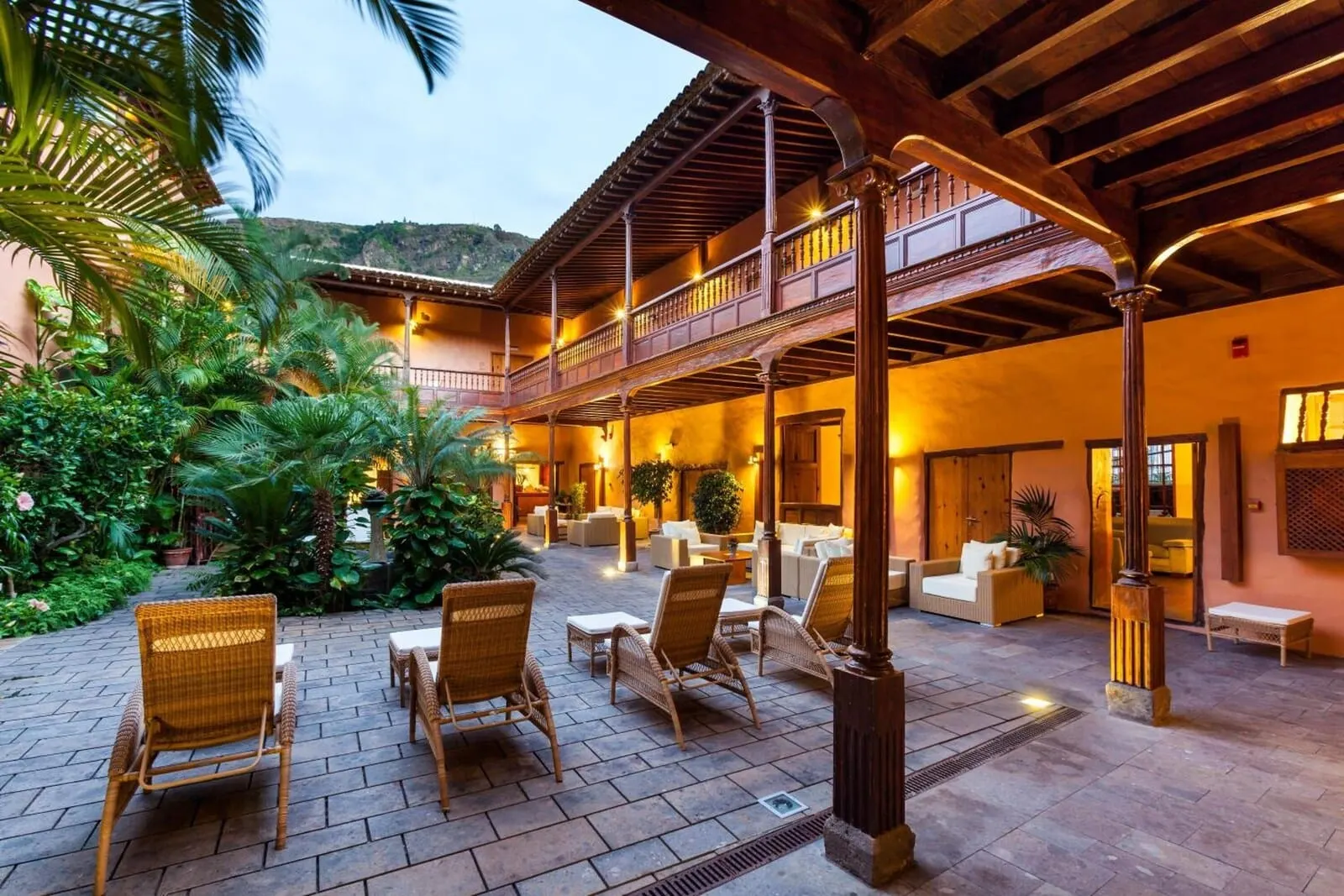 Hotel La Quinta Roja: A spacious outdoor patio with wicker furniture, a wooden balcony, and lush greenery