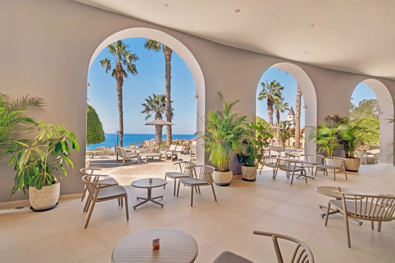 Bahia Principe Escape Tenerife: A spacious outdoor lounge area with multiple seating arrangements, potted plants