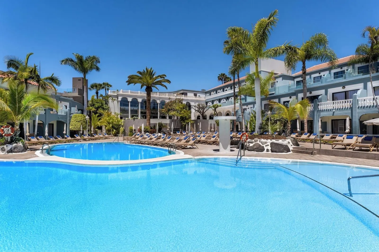 Hotel Colón Guanahaní: A pool area with lounge chairs and palm trees