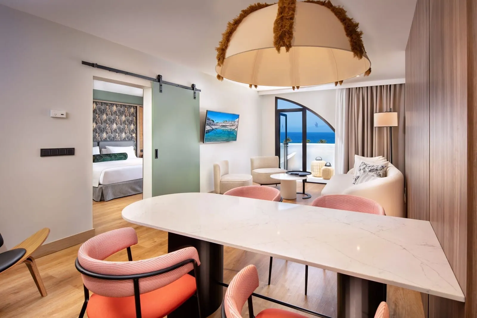 Princess Inspire Tenerife: A modern hotel room with a dining area, a sofa, and a view of the sea